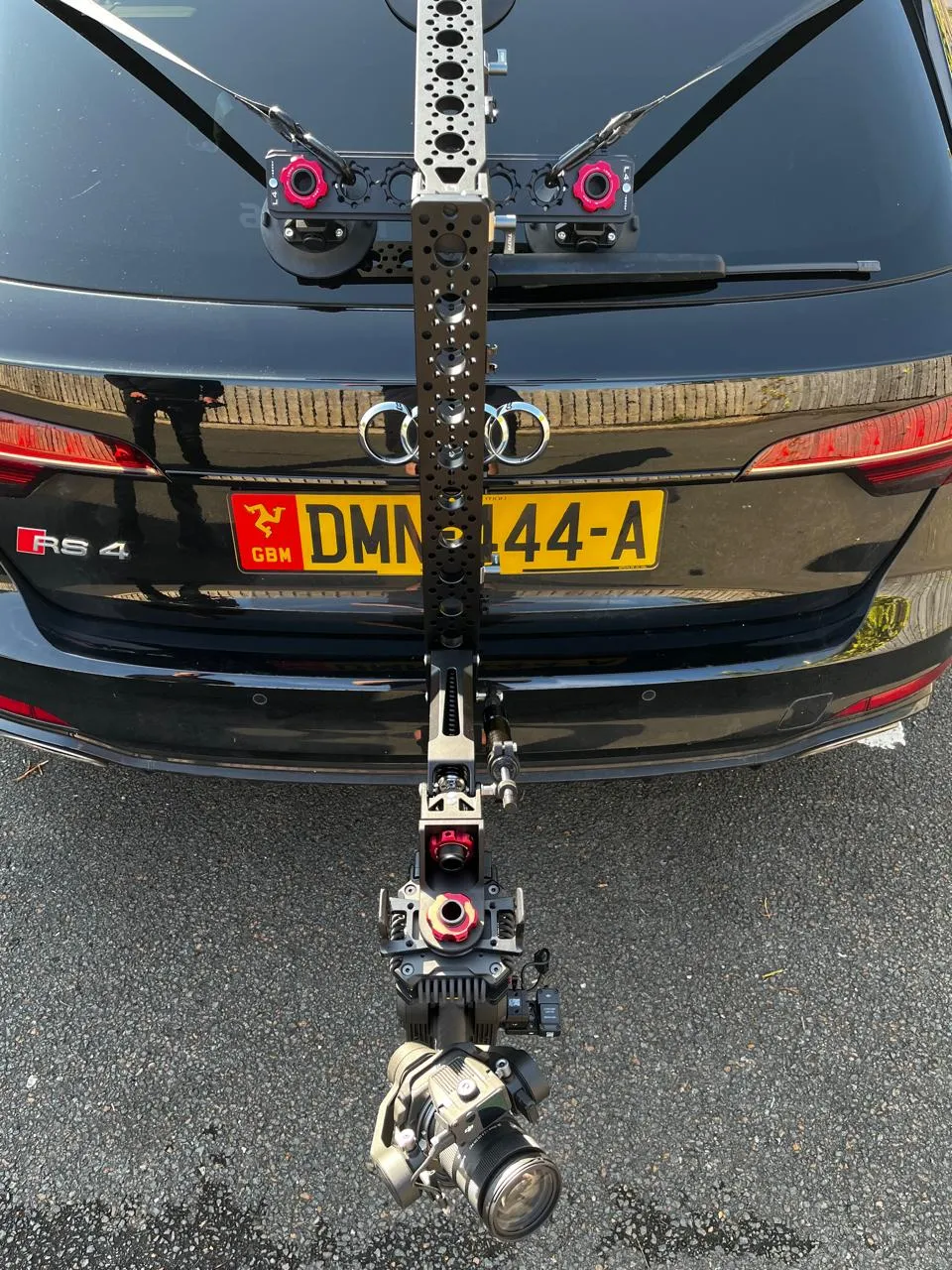 Tilta Hydra Alien arm and DJI Ronin 4D cinema camera mounted low on the rear of a black Audi RS4 on the Isle of Man, showing the full camera rig in position for a vehicle-mounted shoot
