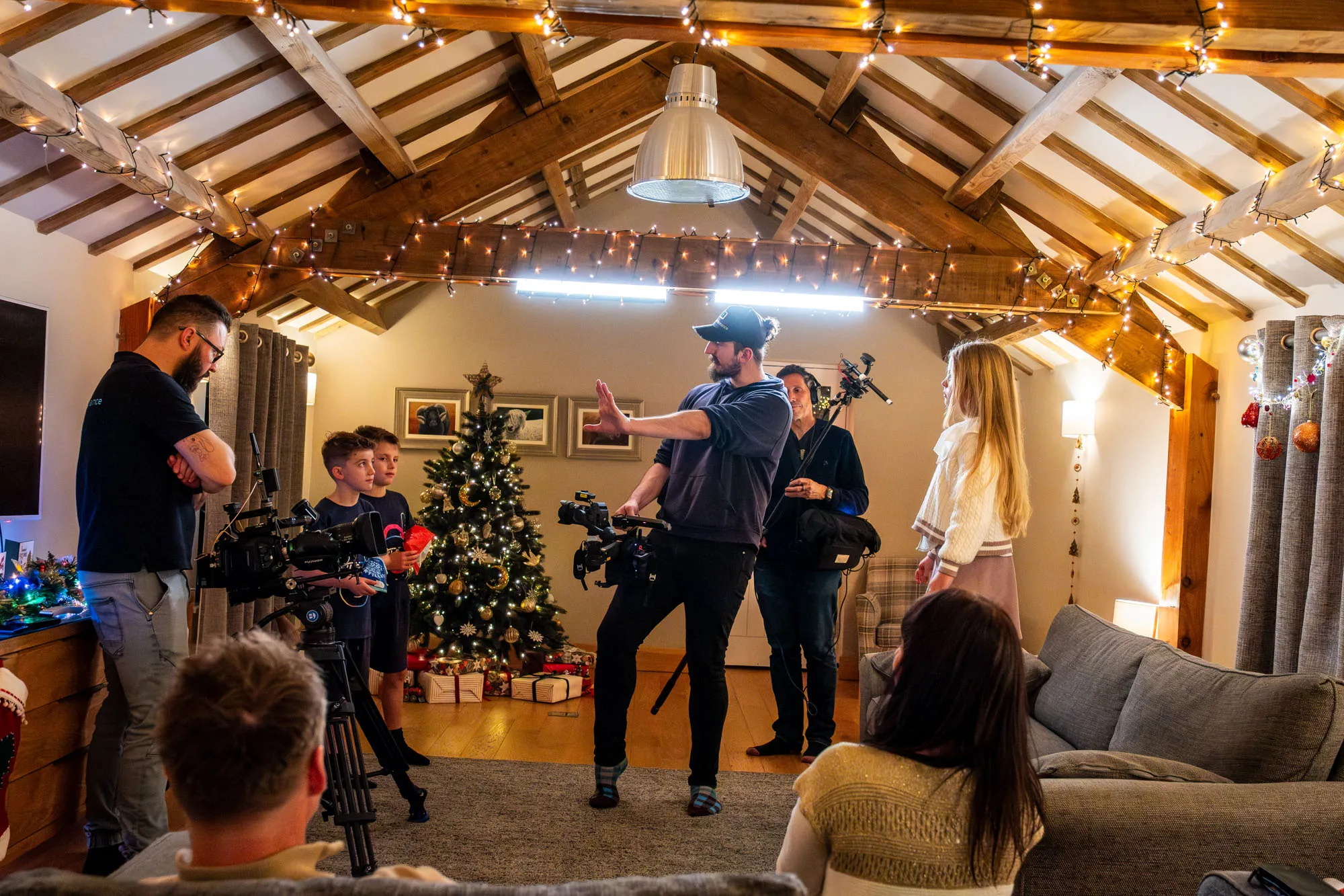 Will Oates directing Arthur Orton, Albert Orton, Vivi Quaye John Beaty, Raluca Matei Orton, Nico van Loggerenberg and Dave Armstrong in a Christmas decorated barn interior at The Barn at Ballaloaghtan, Isle of Man, during production of the Business Isle of Man Buy Local Christmas campaign by DotPerformance