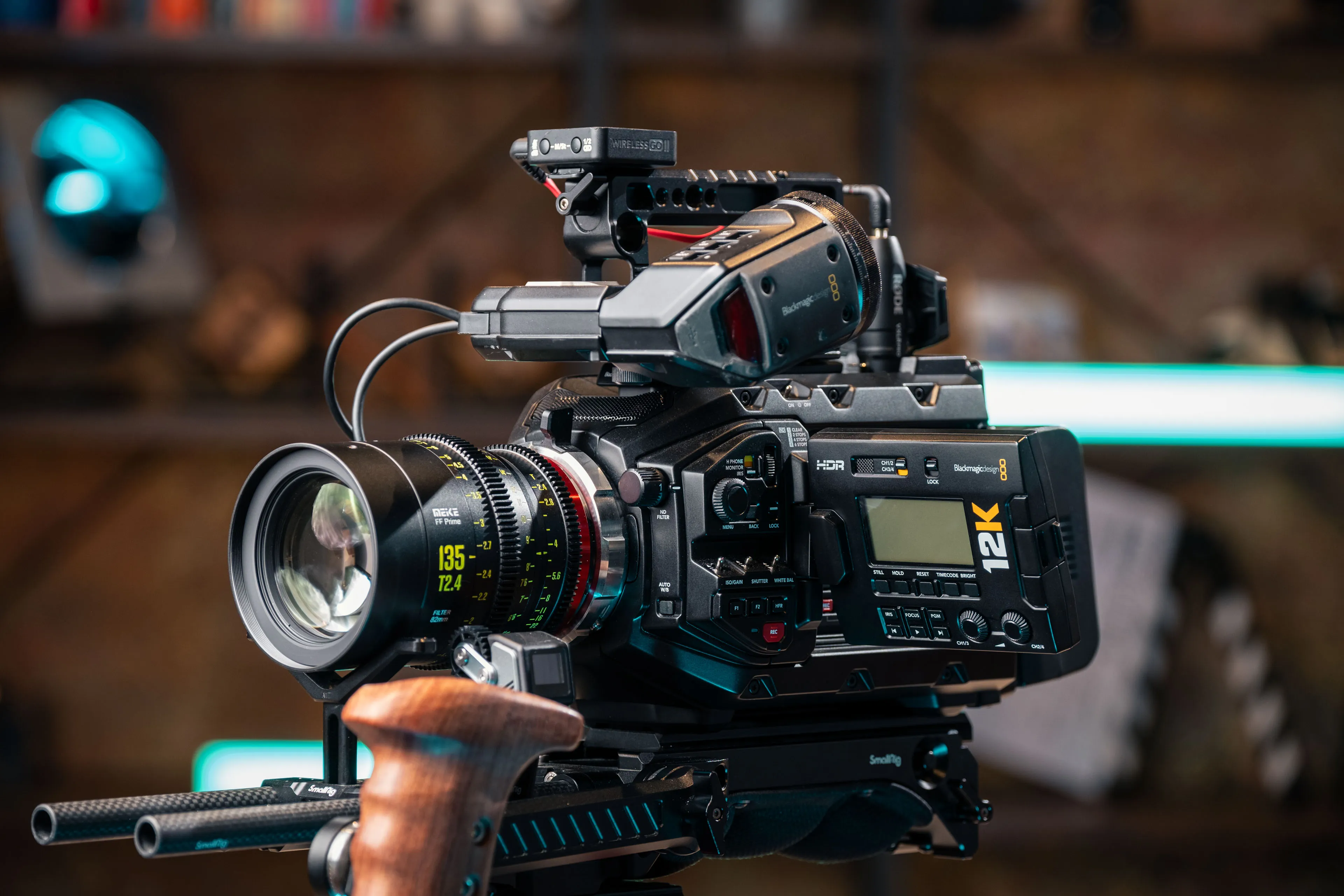 A high-end cinematic camera featuring a large lens and external microphone, set against a blurred background with modern lighting.
