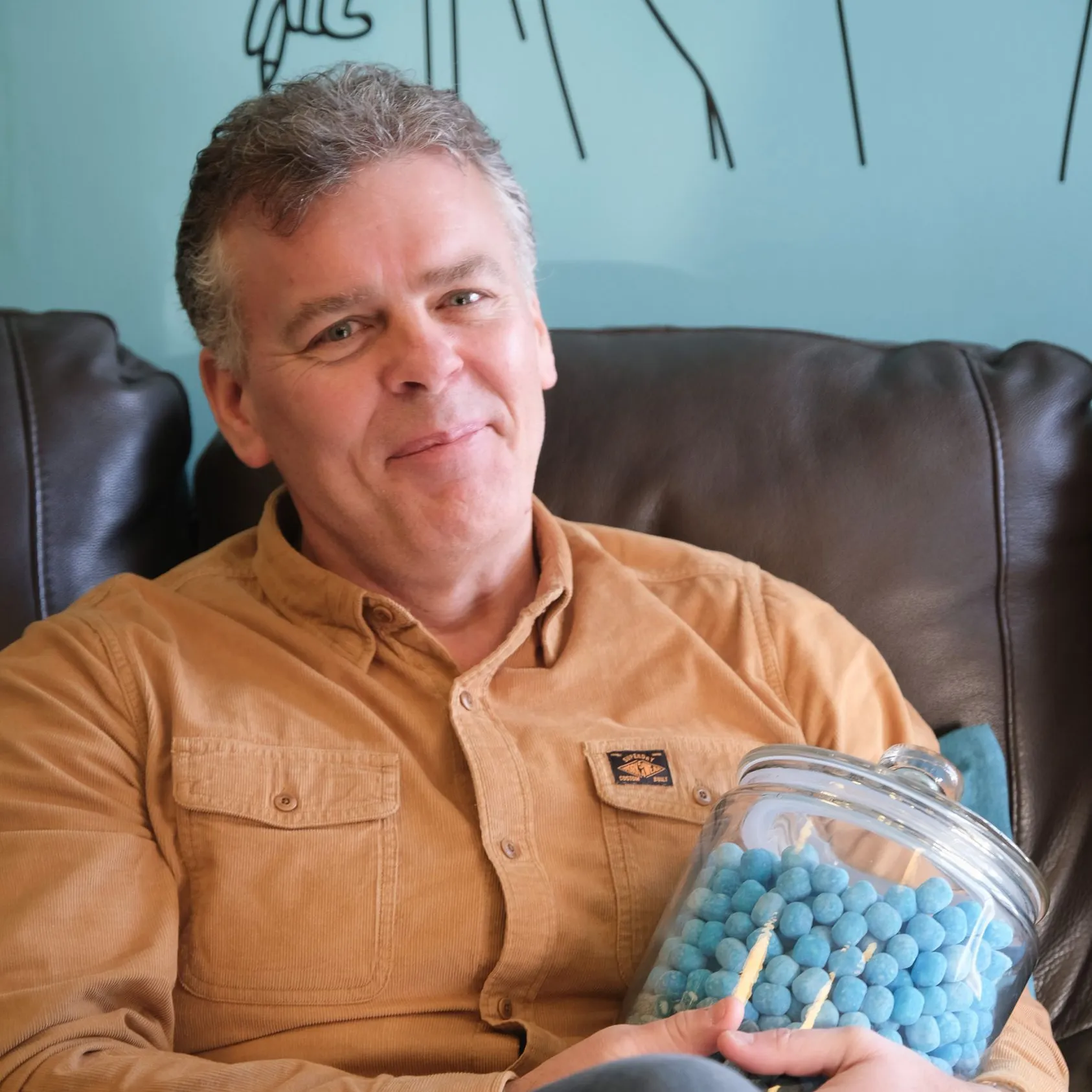 Jason Burton relaxing in the DotPerformance office in Douglas, Isle of Man, holding a jar of blue sweets