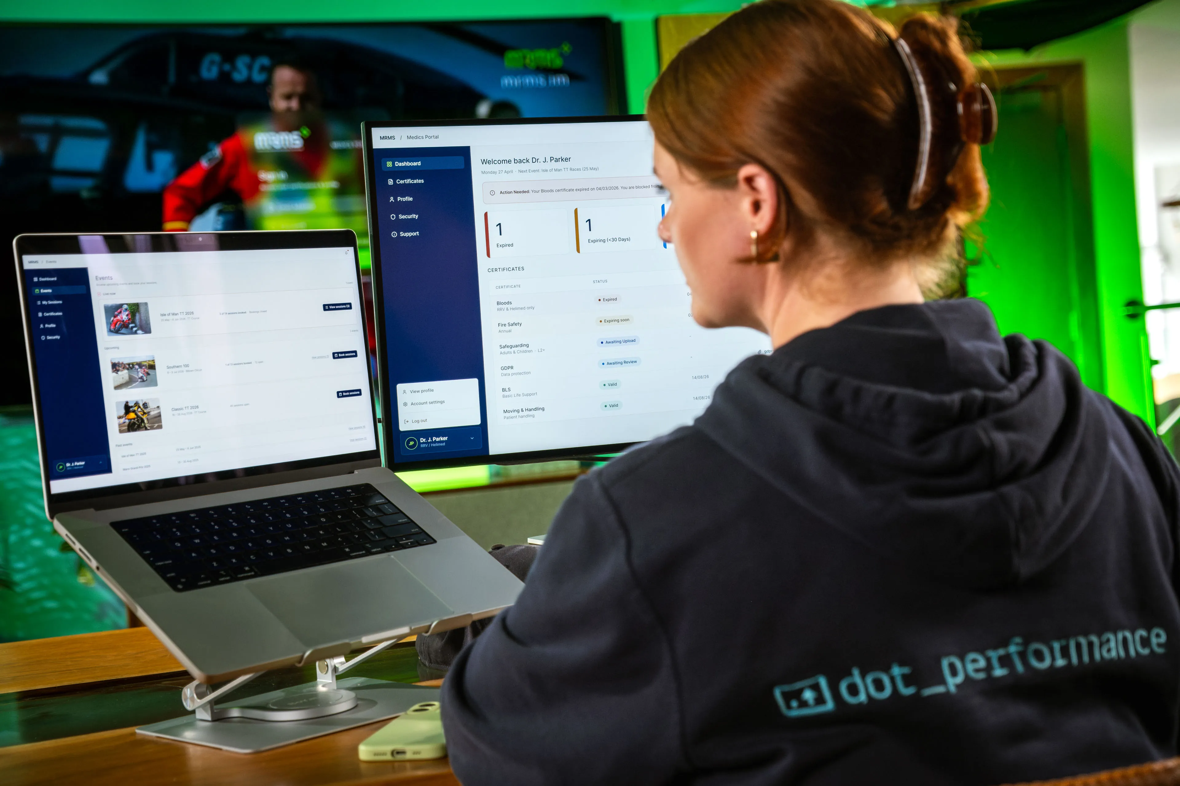 Paula Hamilton checking the MRMS content management system across a MacBook and monitor in the DotPerformance office