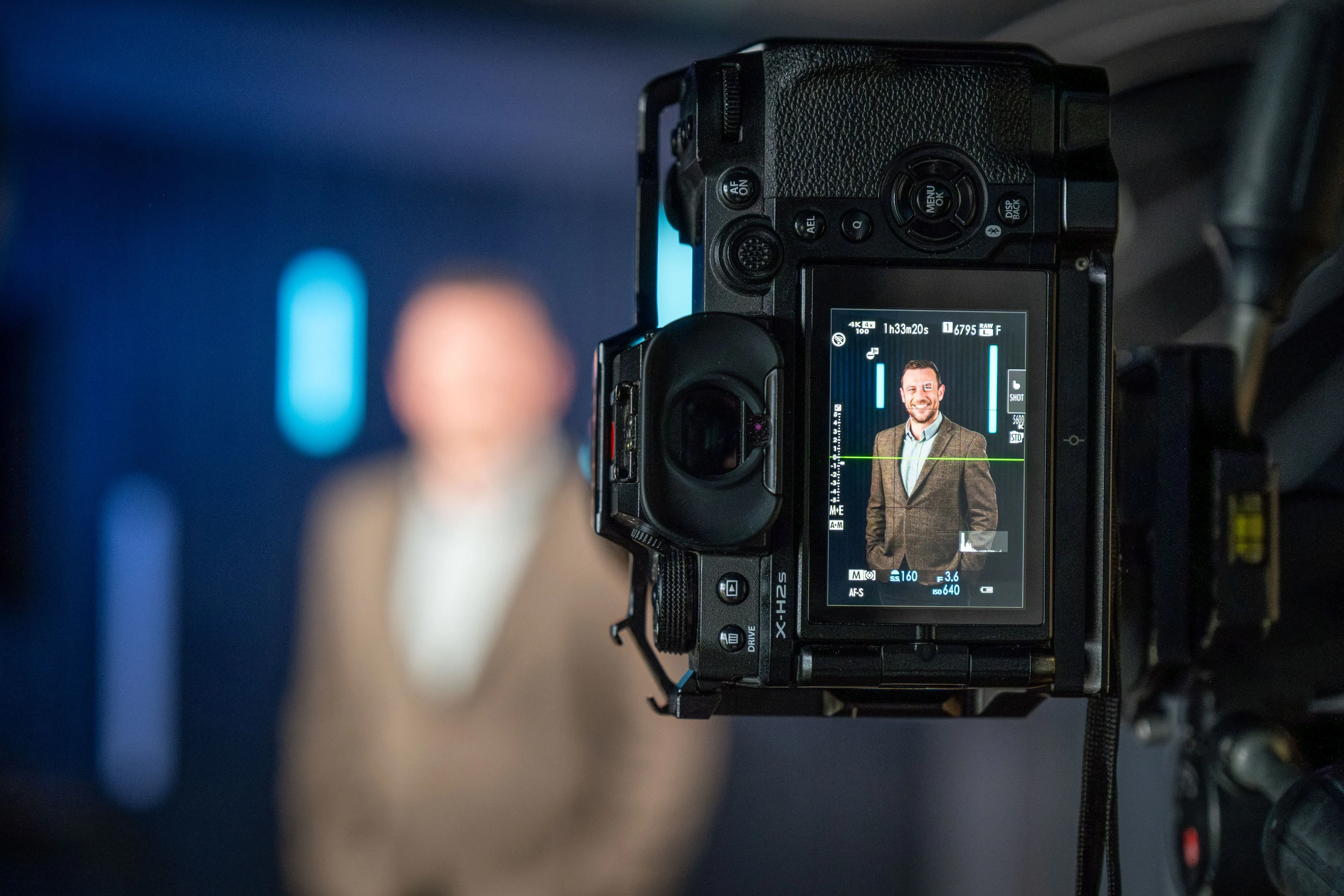 Camera screen showing a live preview of an ECAP employee's headshot, framed and lit against a blue studio backdrop