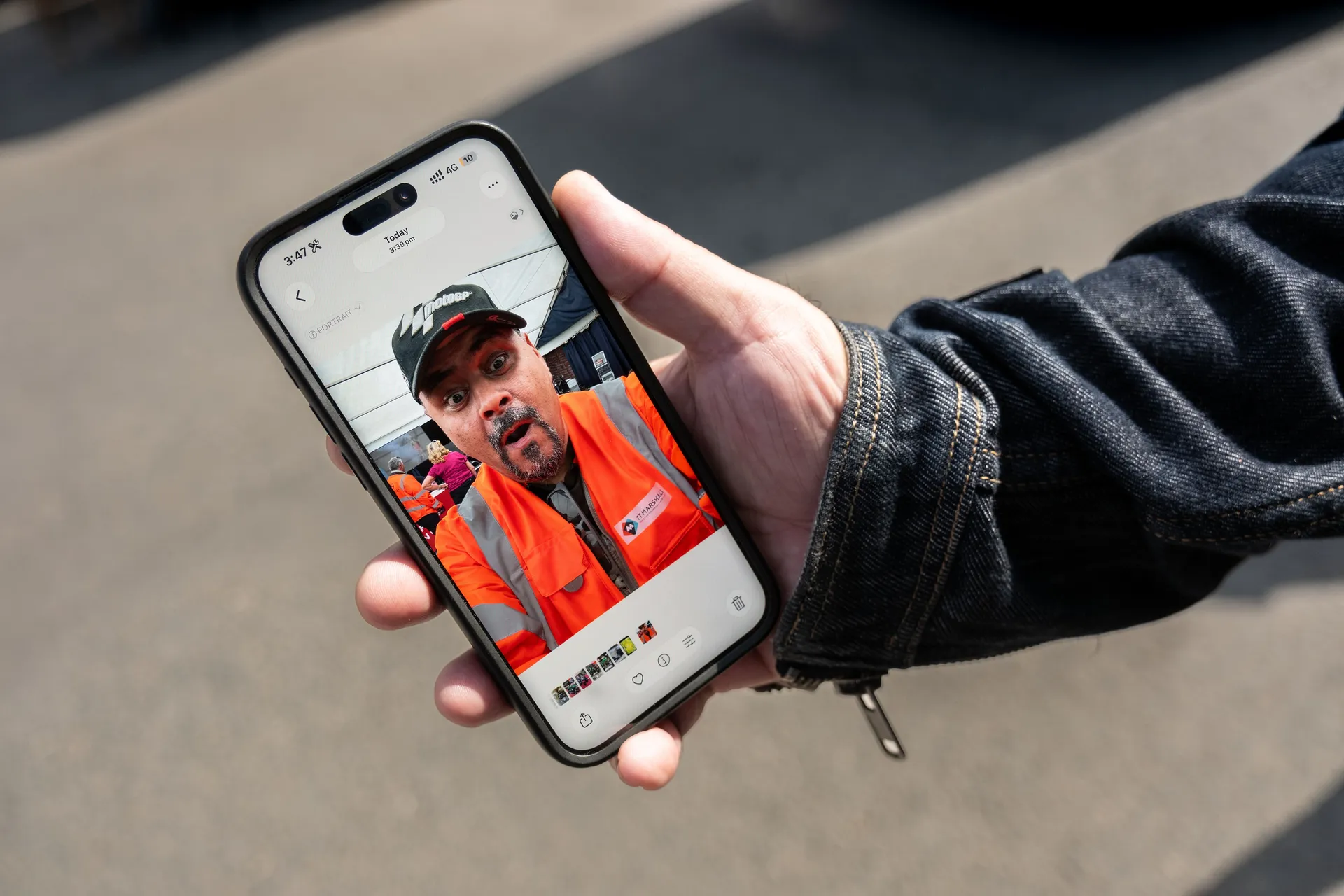 A hand holding a phone showing a Behind the Tabard post of a TT marshal