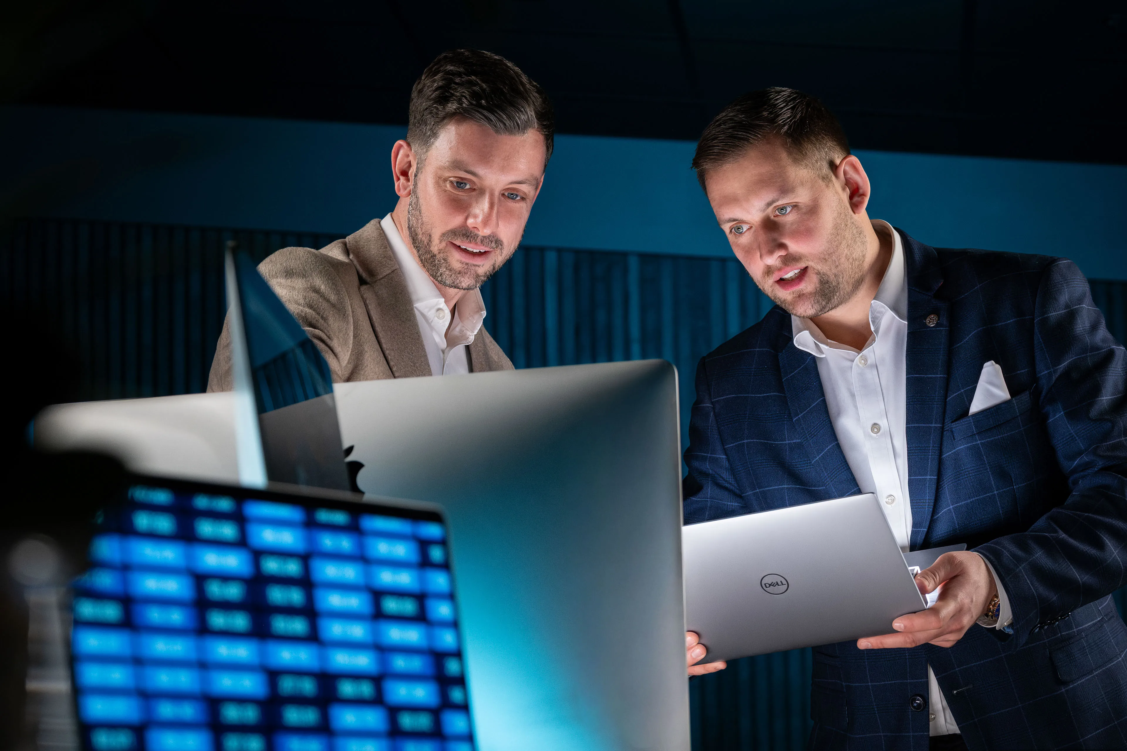 Dan Collier and Brook Longhurst comparing information on a Dell laptop against a desktop monitor during a photoshoot for ECAP