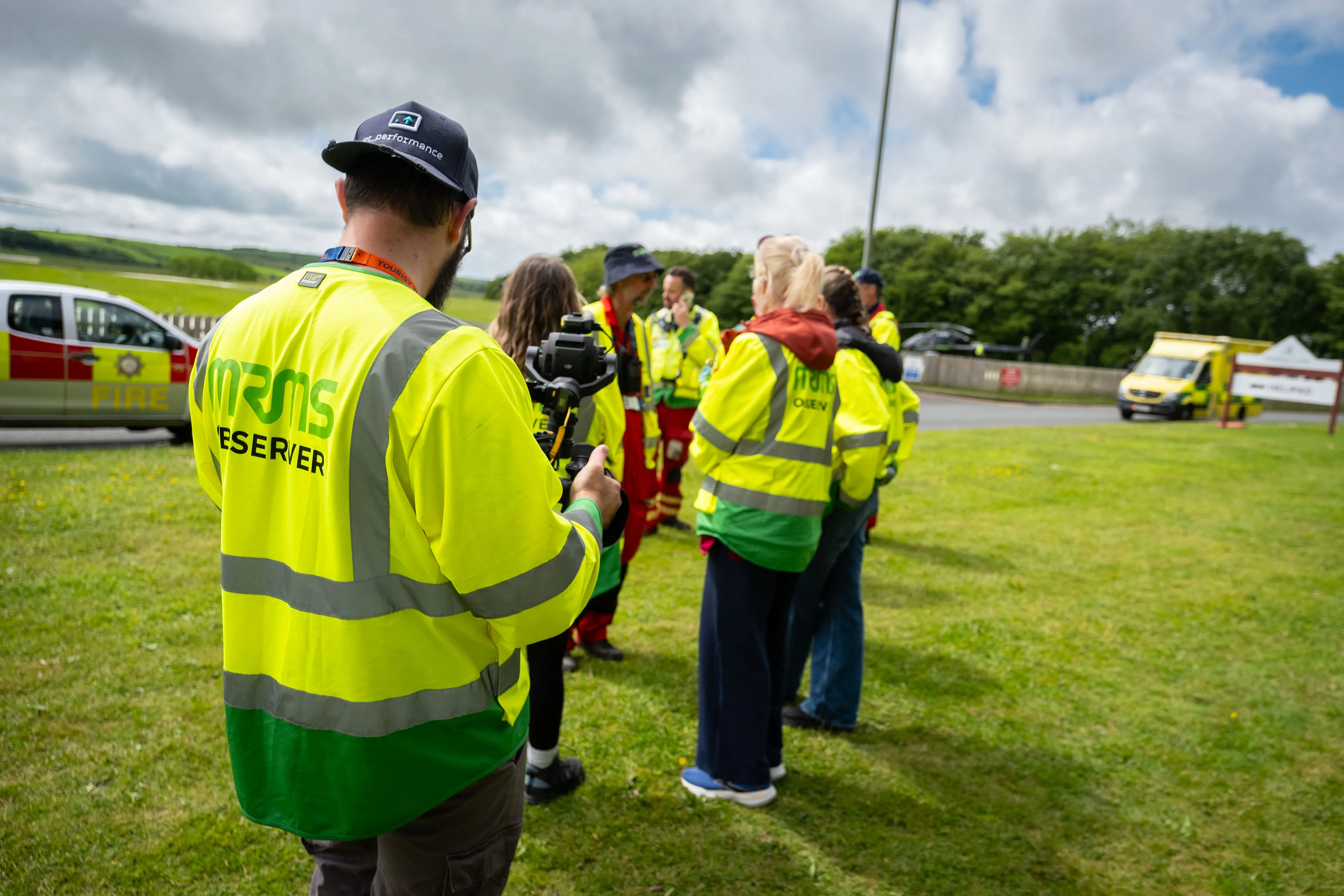 Nico van Loggerenberg filming a group of MRMS team members, including paramedics and observers, during a team talk near the fire and ambulance vehicles
