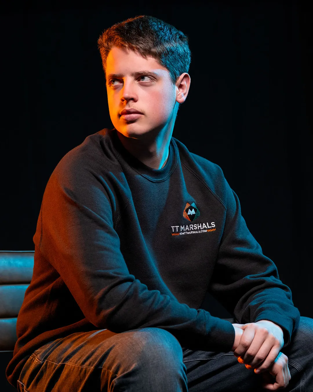 Deane Corlett-Aspell wearing the official TT Marshals 2026 black crewneck jumper, featuring the TT Marshals logo. Exclusive marshal merchandise for the Isle of Man TT 2026.