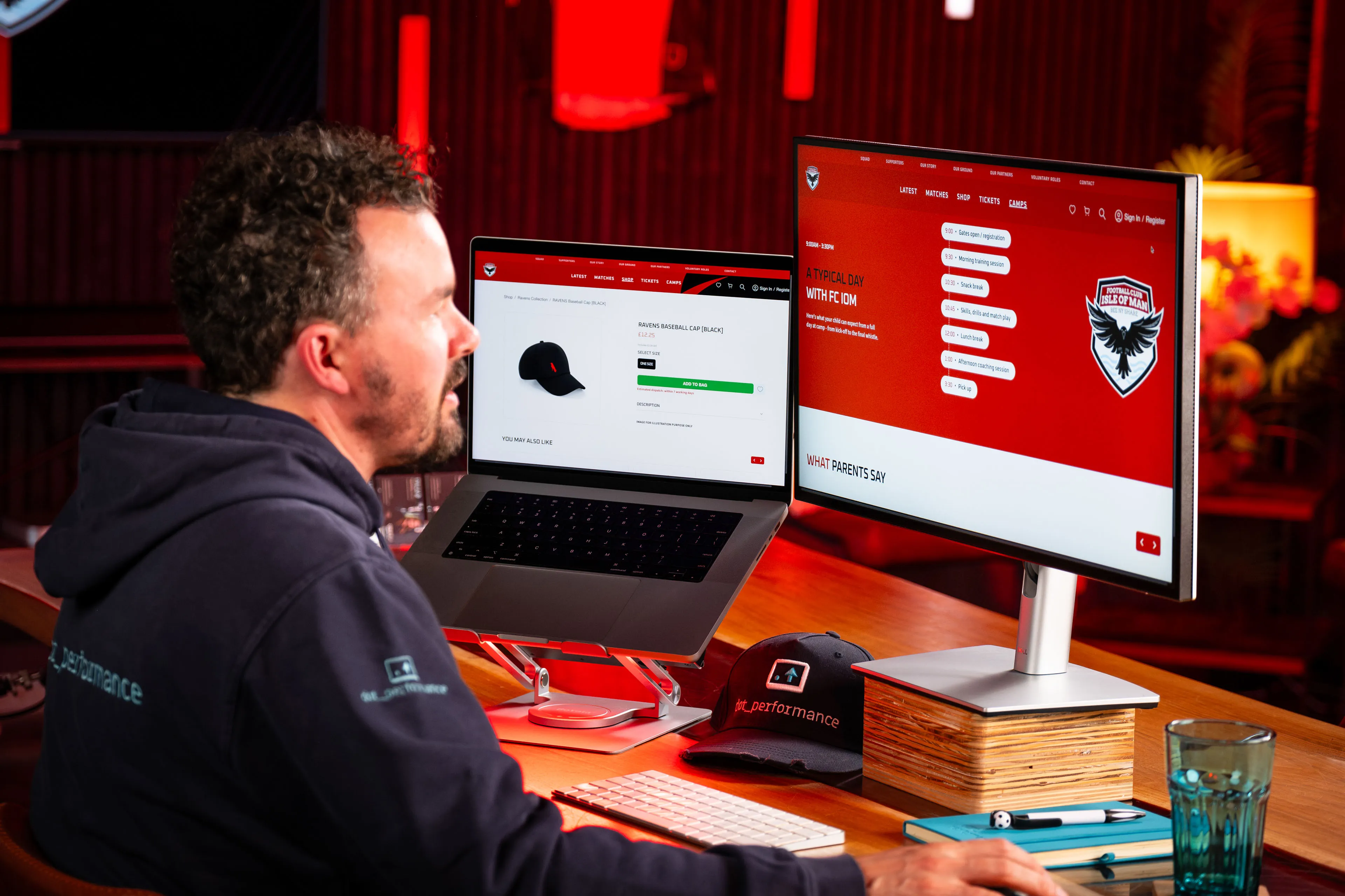 Adrian Crellin browsing the FCIOM Ravens shop on a laptop and the camps page on a monitor at DotPerformance's media studio