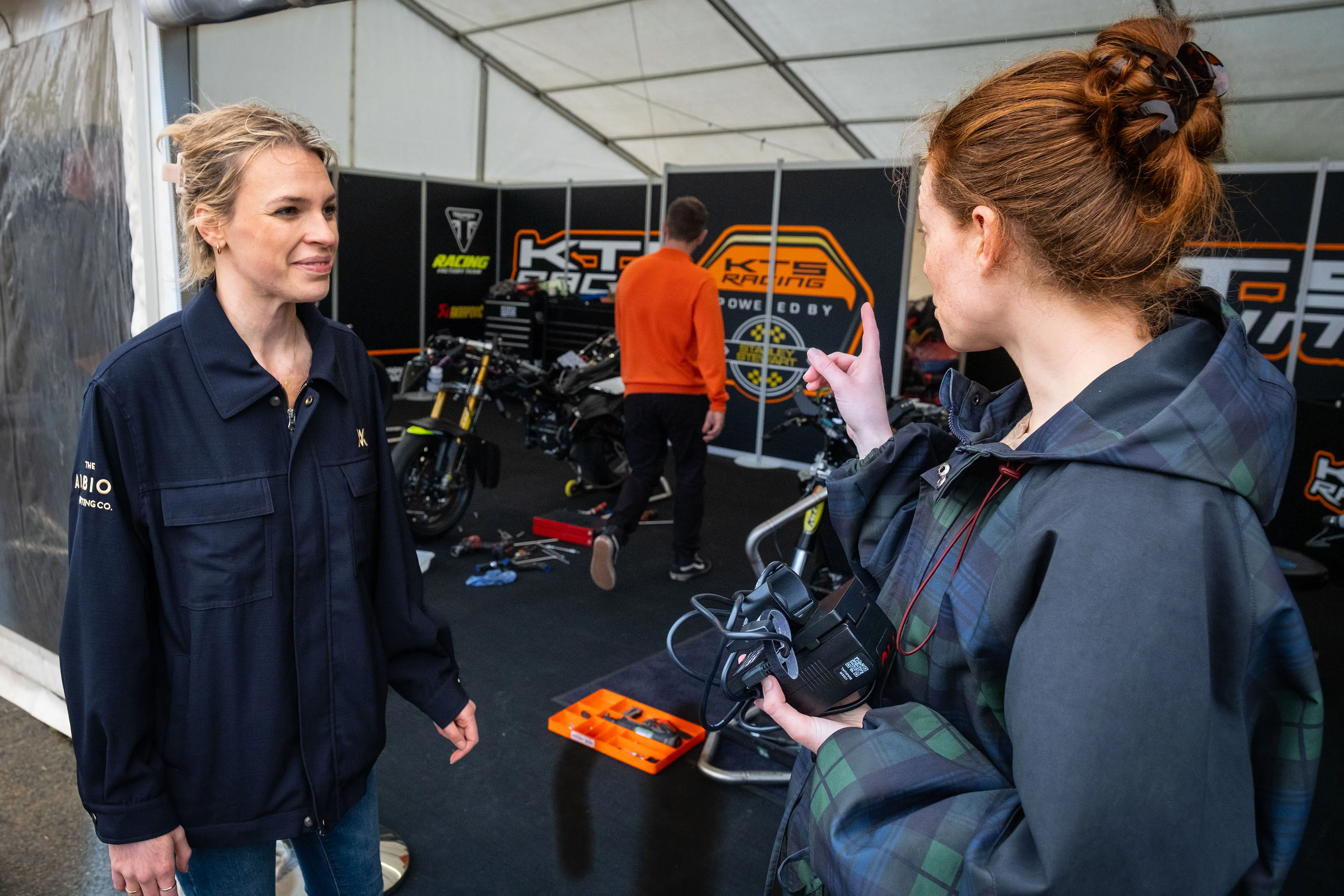 Maddi Scordia and Ella Garvey talking inside the KTS Racing marquee at the Isle of Man TT