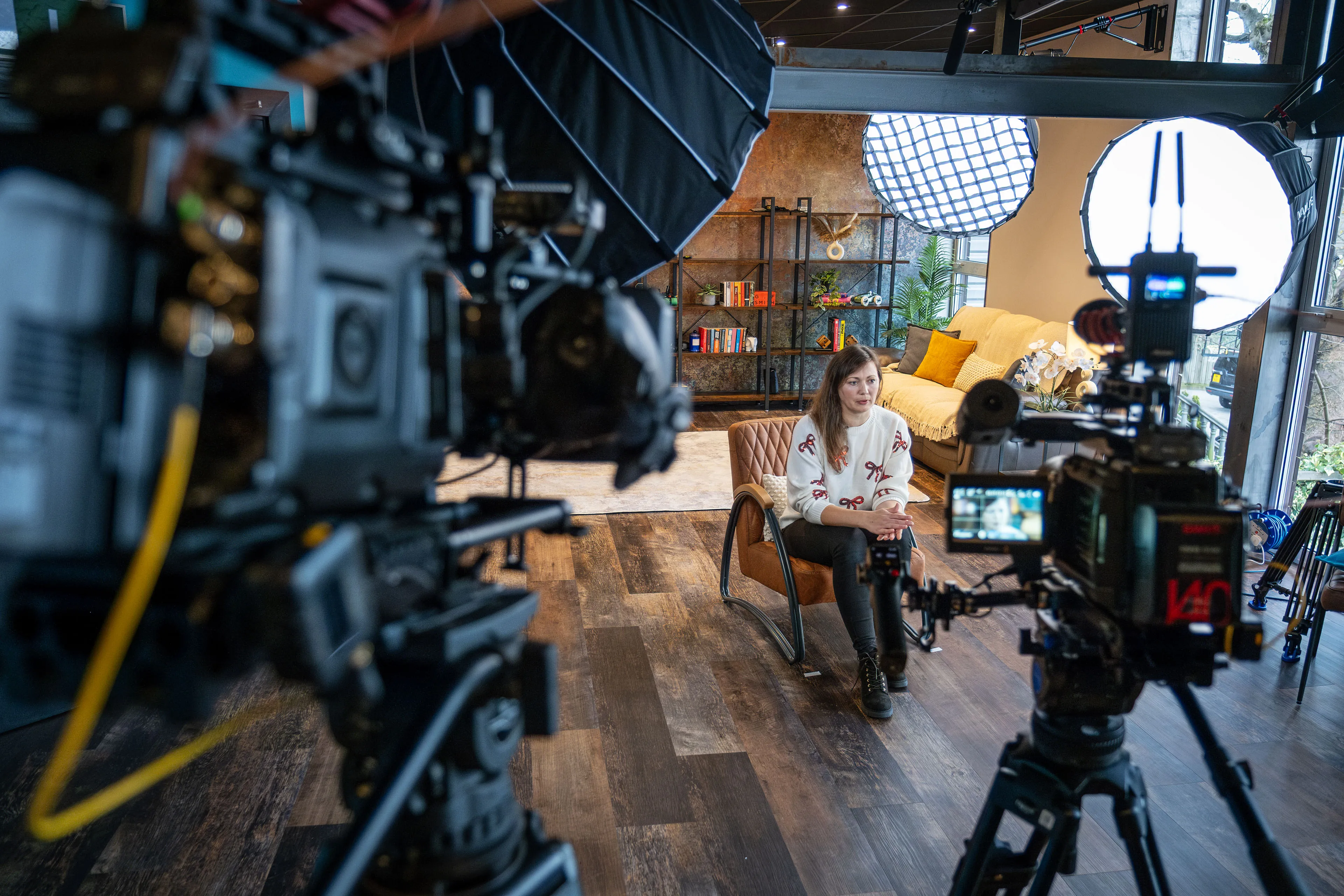 Dual URSA 12K Mini Pro BlackMagic cameras framing Oksana whule she's seated on set during a DotPerformance video production shoot at the Isle of Man studio, with softbox and octabox lighting visible
