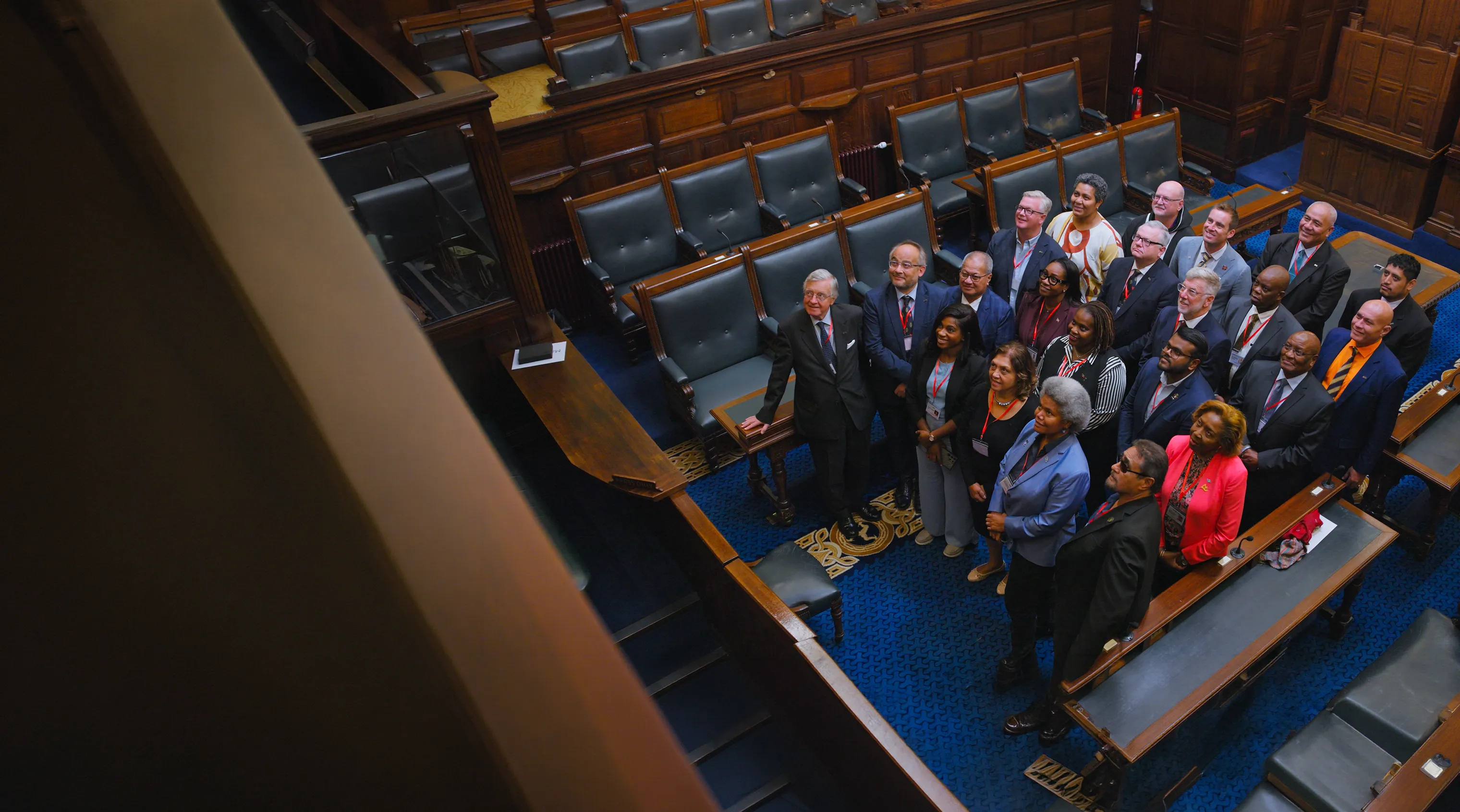 Group of people in a parliamentary chamber looking up.