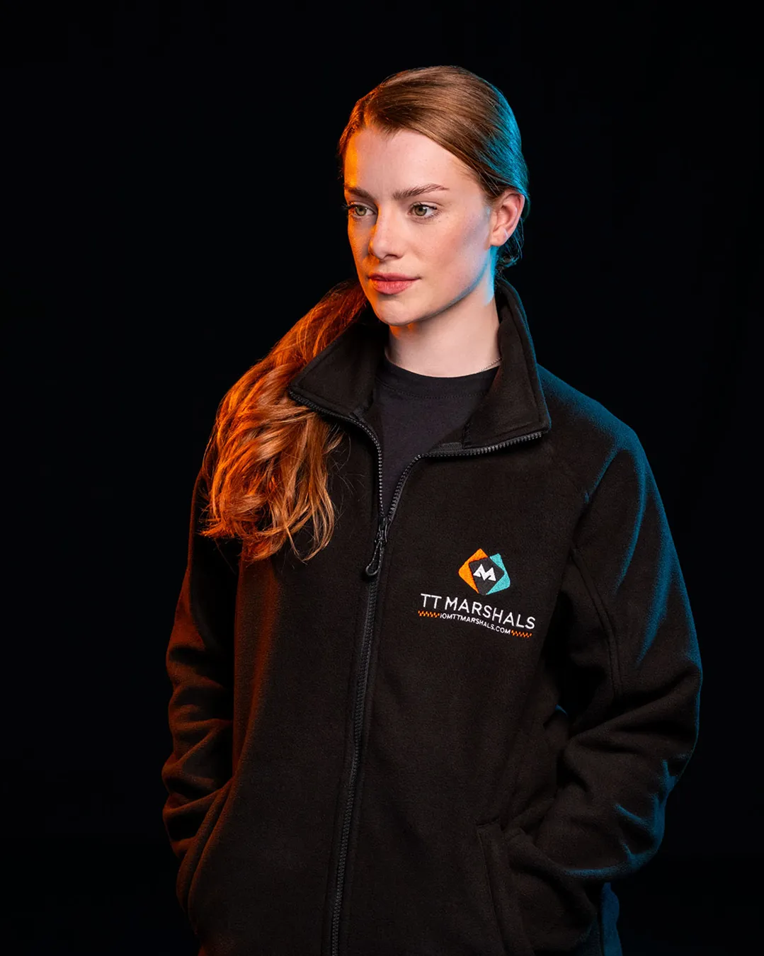 Ella Garvey wearing the official TT Marshals 2026 black fleece, featuring the TT Marshals logo. Exclusive marshal merchandise for the Isle of Man TT 2026.