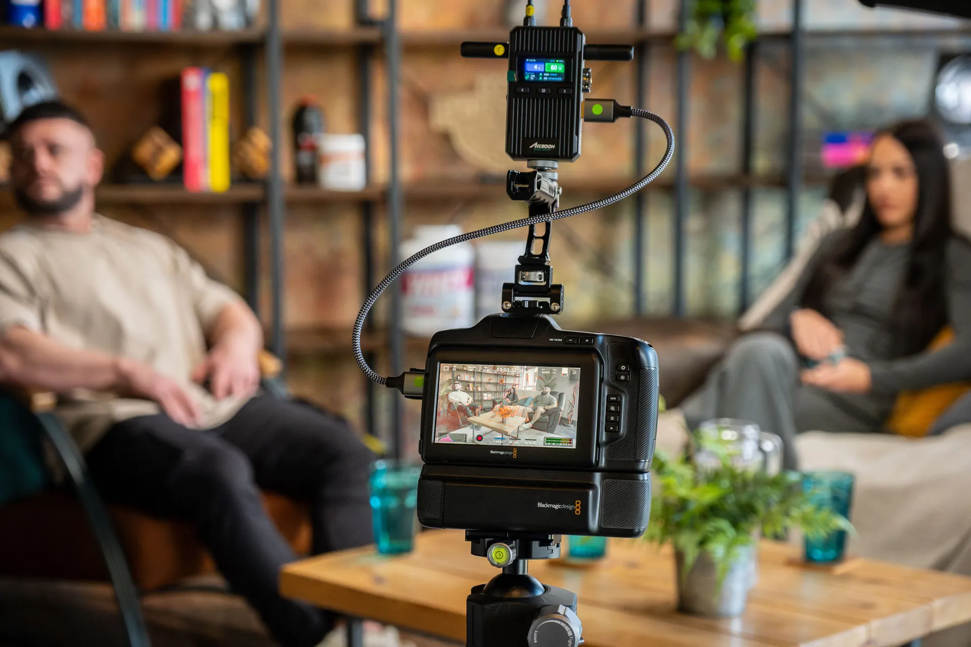 Blackmagic Pocket Cinema Camera 6K Pro with an Accsoon wireless transmitter mounted on a tripod in the DotPerformance podcast studio on the Isle of Man, with Danny Hands and Christie Hands seated in the background