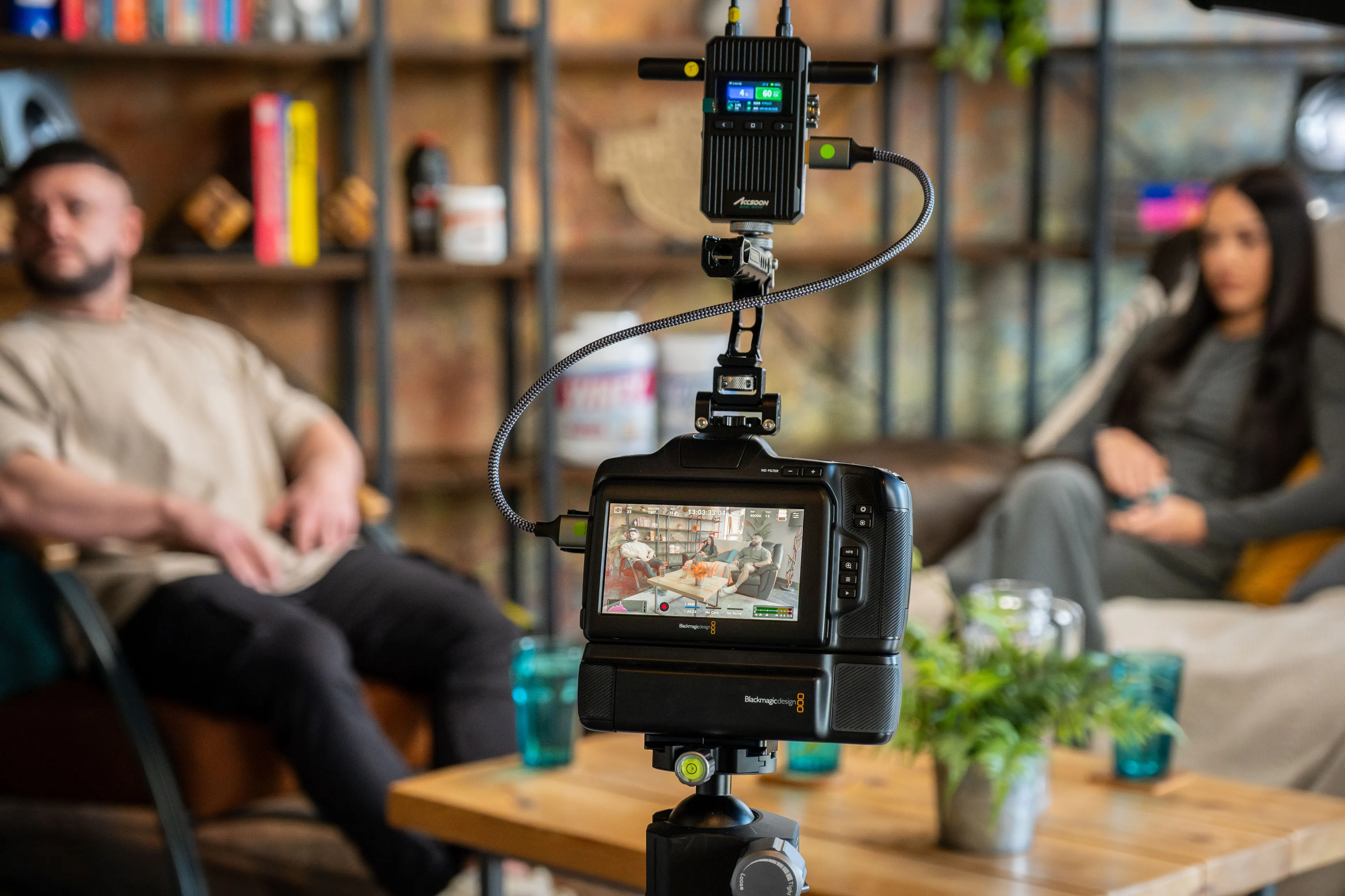 Blackmagic Pocket Cinema Camera 6K Pro with an Accsoon wireless transmitter mounted on a tripod in the DotPerformance podcast studio on the Isle of Man, with Danny Hands and Christie Hands seated in the background