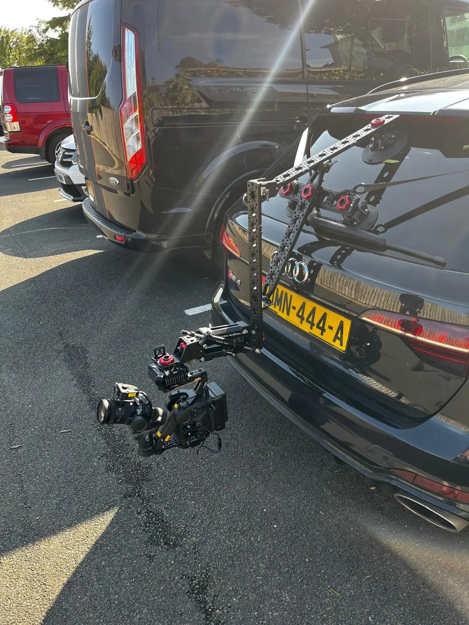 DJI Ronin 4D cinema camera on a Tilta Hydra Alien arm mounted low at the rear of a black Audi RS4, showing the low-angle vehicle rig position used by DotPerformance on the Isle of Man