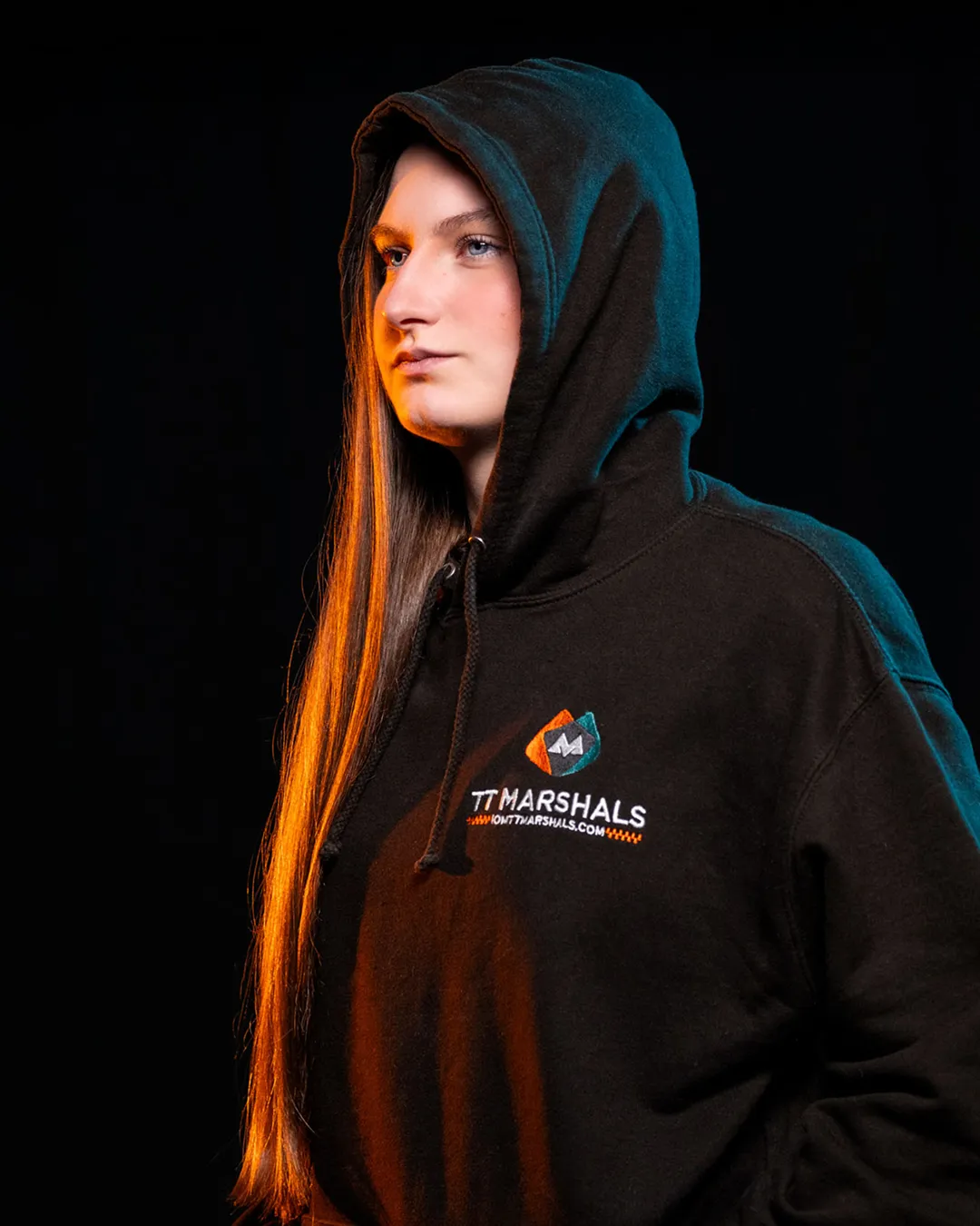 Caitlin Hampson wearing the official TT Marshals 2026 black hoodie, featuring the TT Marshals logo. Exclusive marshal merchandise for the Isle of Man TT 2026.