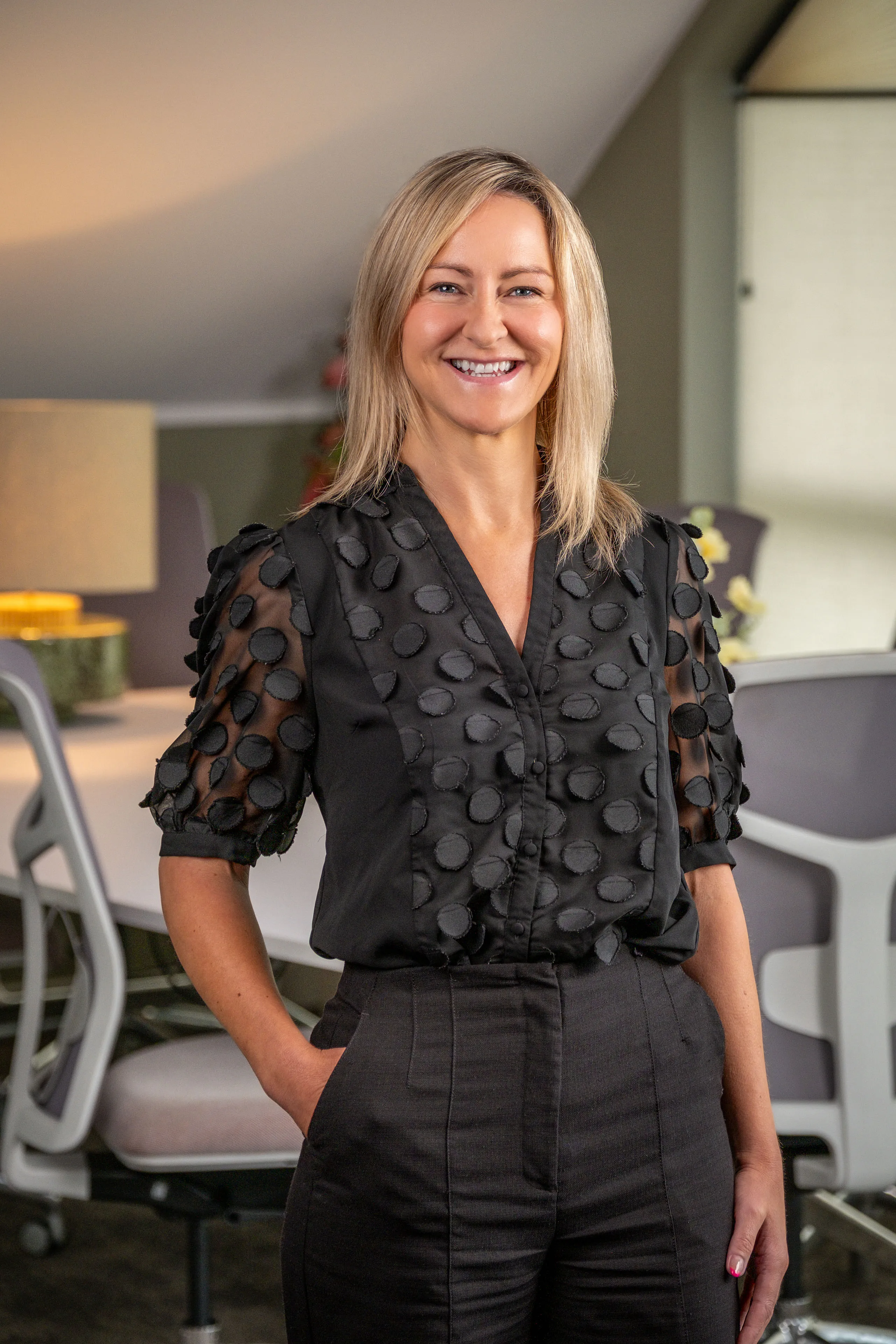 Professional headshot of Sue Coniglio-Burrows smiling in a black appliqué blouse, taken during the Boal & Co 2026 portrait session