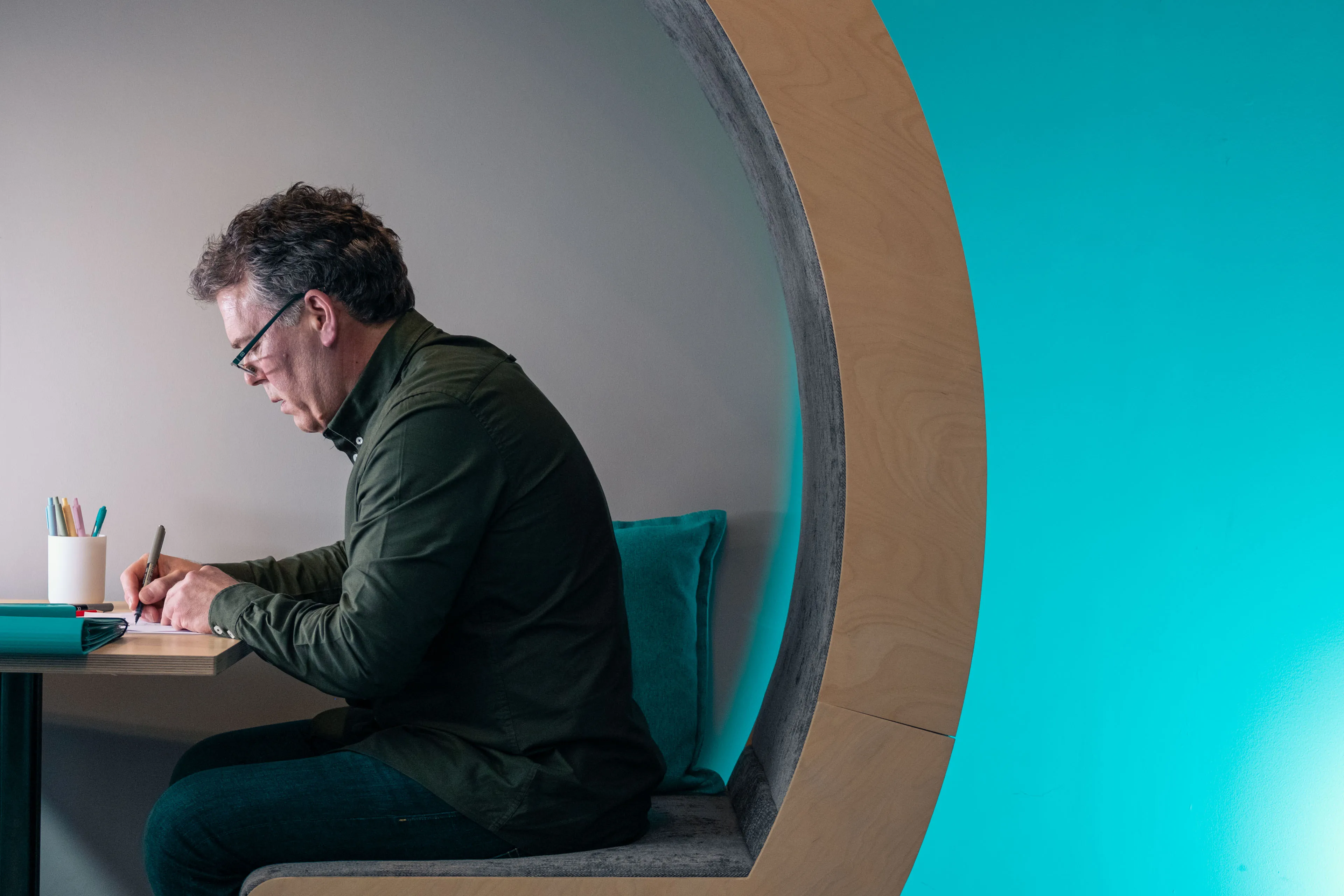 Jason Burton making notes in a quiet work booth at the DotPerformance office in Douglas, Isle of Man