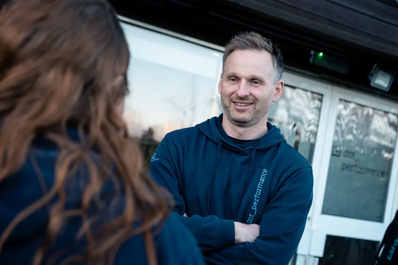 John, head of systems at Dot Performance is seen with his arms crossed smiling, outside the dot performance building.