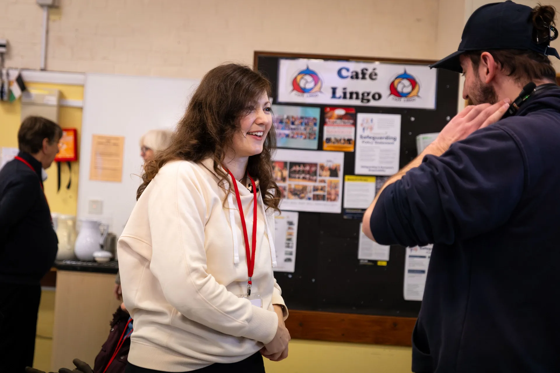 Oksana Fedorovych speaking with Will Oates in front of the Café Lingo noticeboard during documentary filming on the Isle of Man