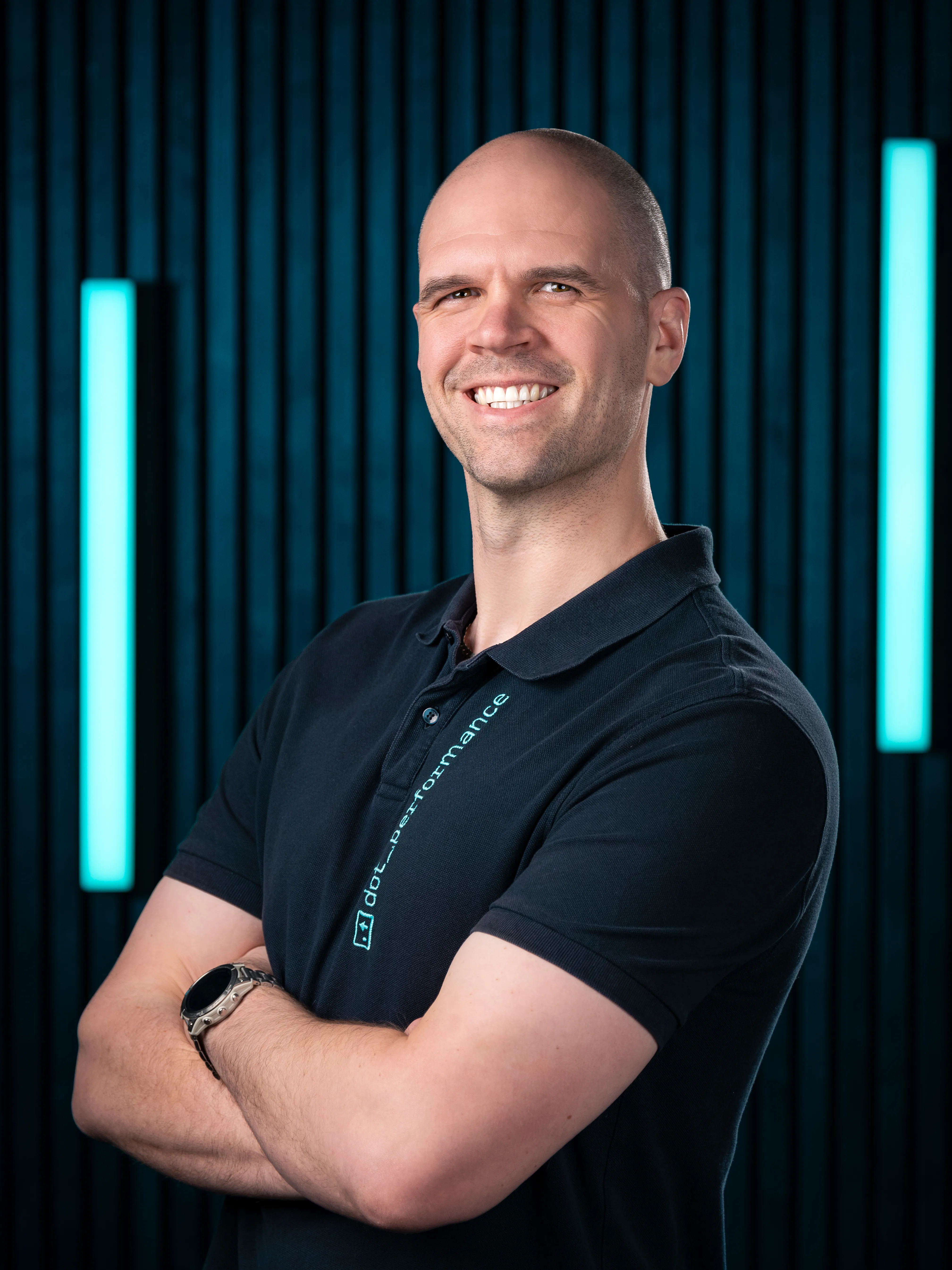 Mark, developer at Dot Performance, smiling with crossed arms as he poses for headshot wearing branded polo shirt.