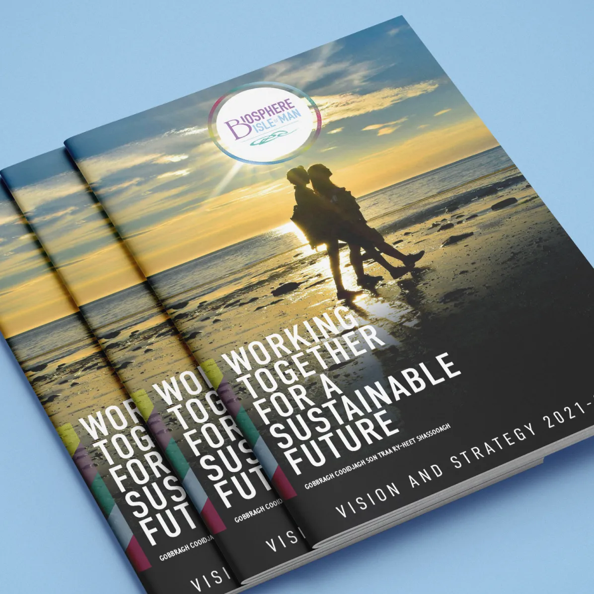 Three copies of the Biosphere Isle of Man Vision and Strategy 2021–2026 printed booklet stacked at an angle, showing the beach sunset cover design by DotPerformance