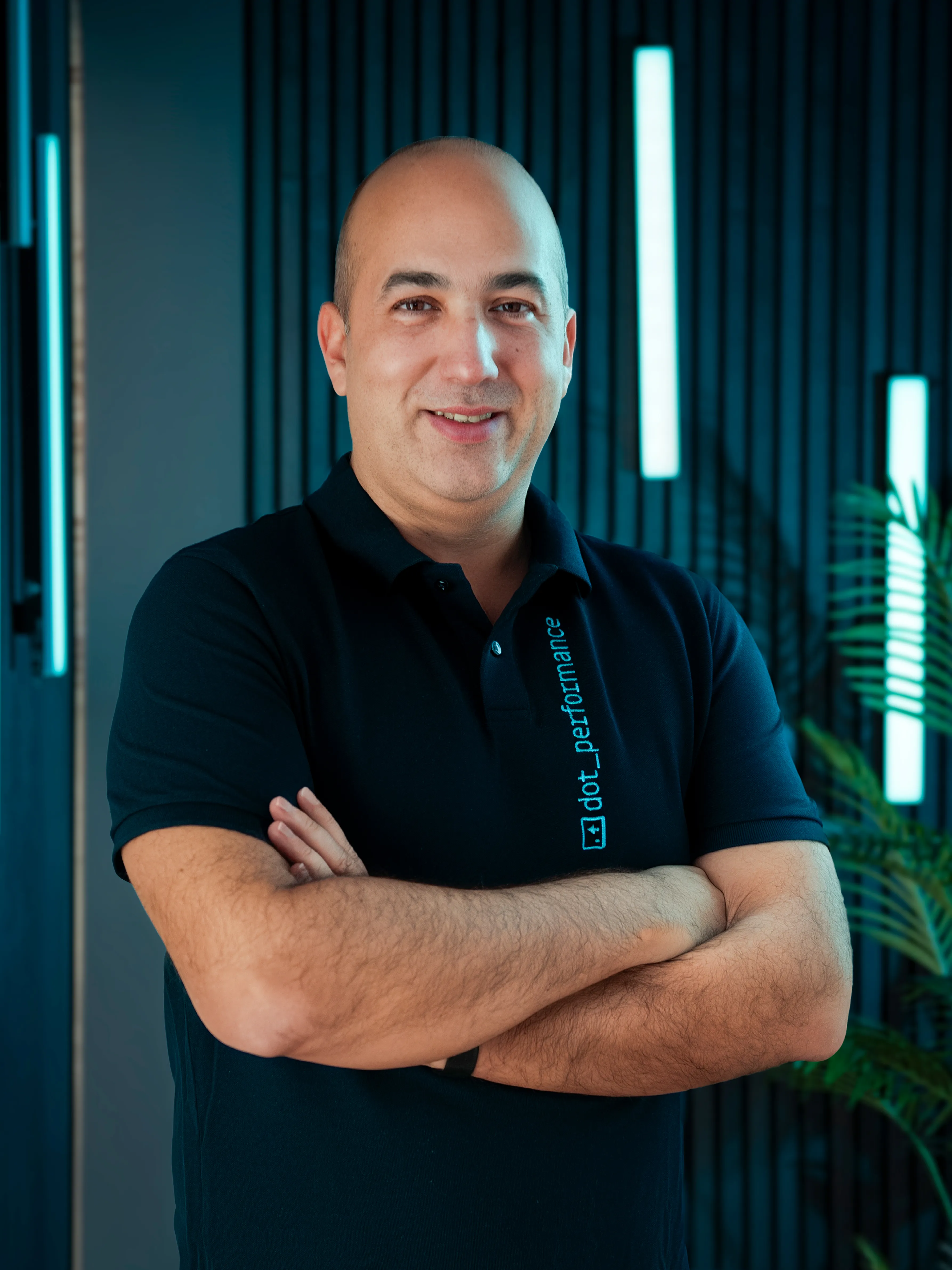 Claudiu, senior developer at Dot Performance, smiling with crossed arms as he poses for headshot wearing branded polo shirt.