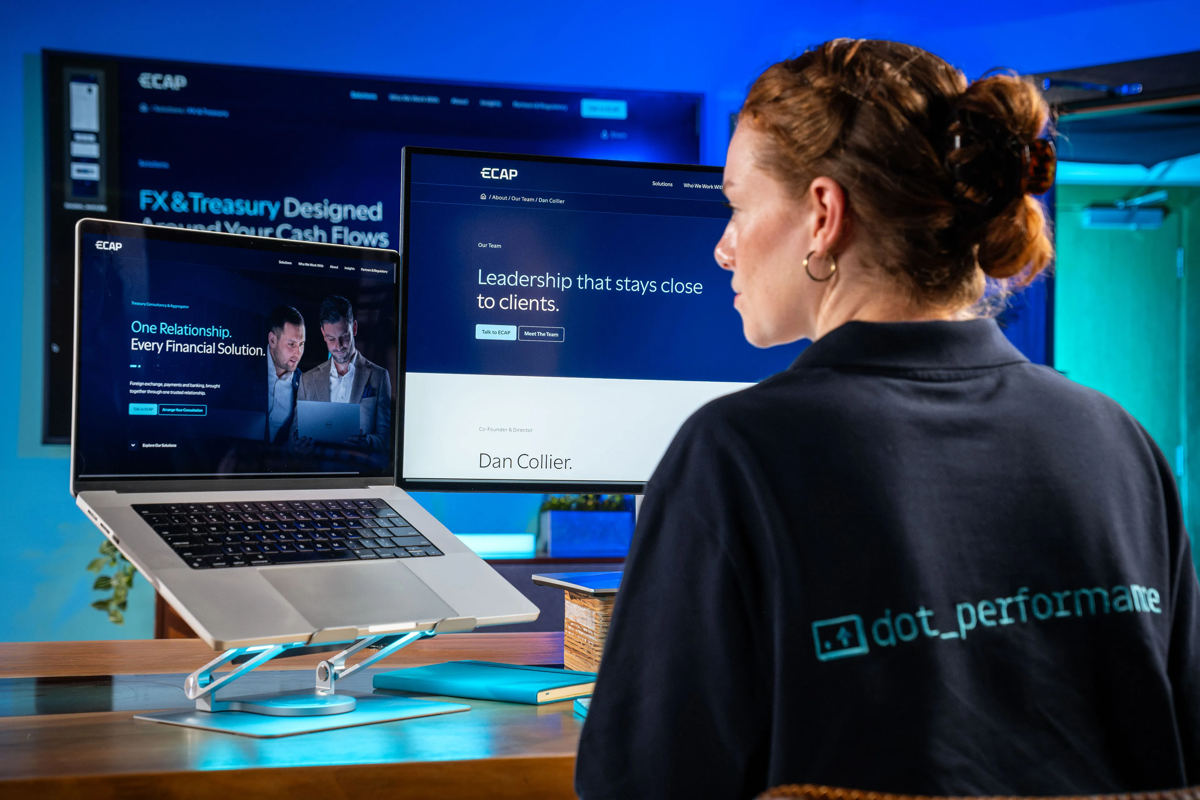 Over-the-shoulder view of Ella Garvey working on the ECAP website, with Dan Collier and Brook Longhurst on screen
