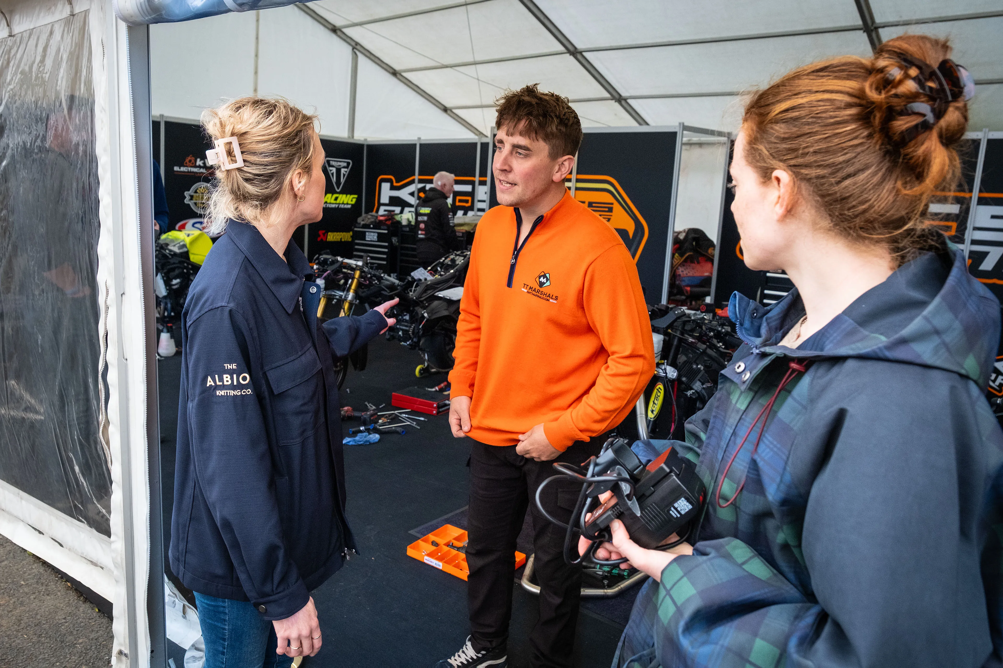 Maddi Scordia talking with Dom Herbertson and Ella Garvey inside the KTS Racing marquee at the Isle of Man TT