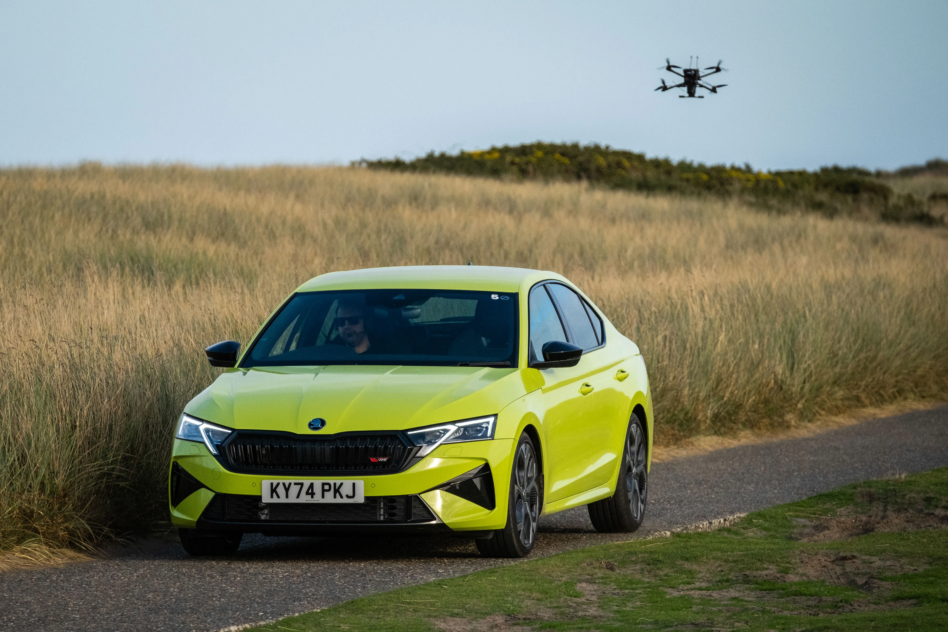 Lime green Skoda RS filmed on location on the Isle of Man by DotPerformance, with an FPV cinelifter drone visible in the background during a commercial video production shoot