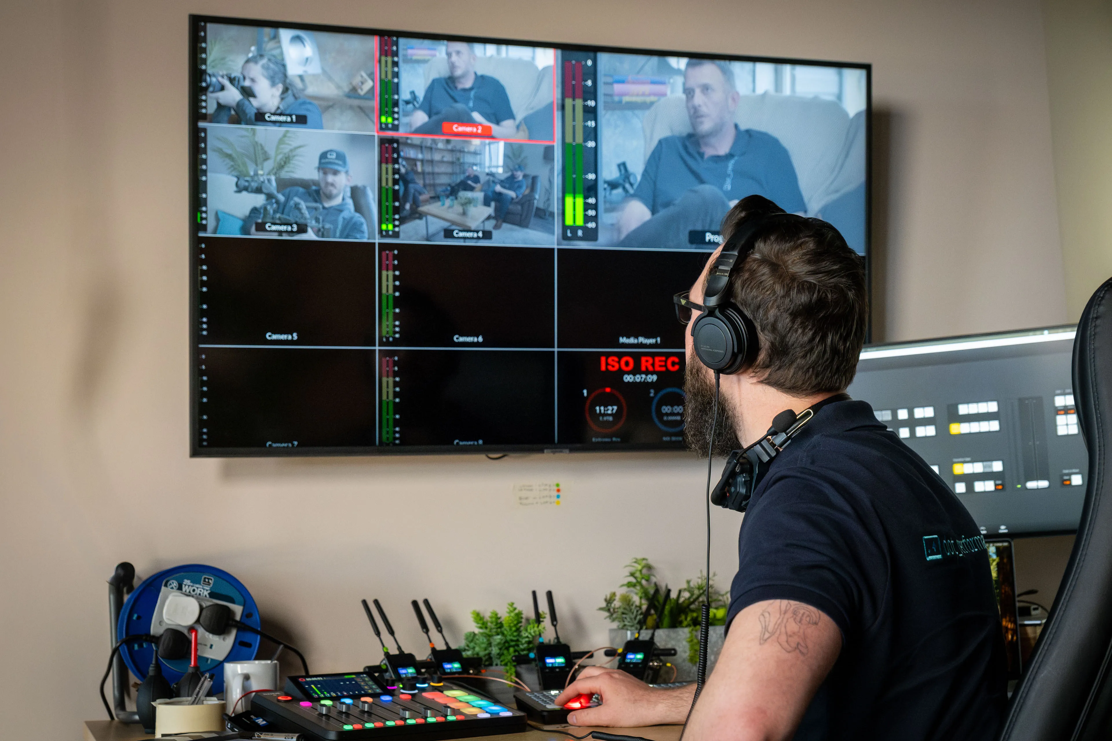 Nico van Loggerenberg operating a live video switcher (ATEM) and multi-camera monitor at the Isle of Man studio, with four camera feeds and ISO recording visible on screen,.