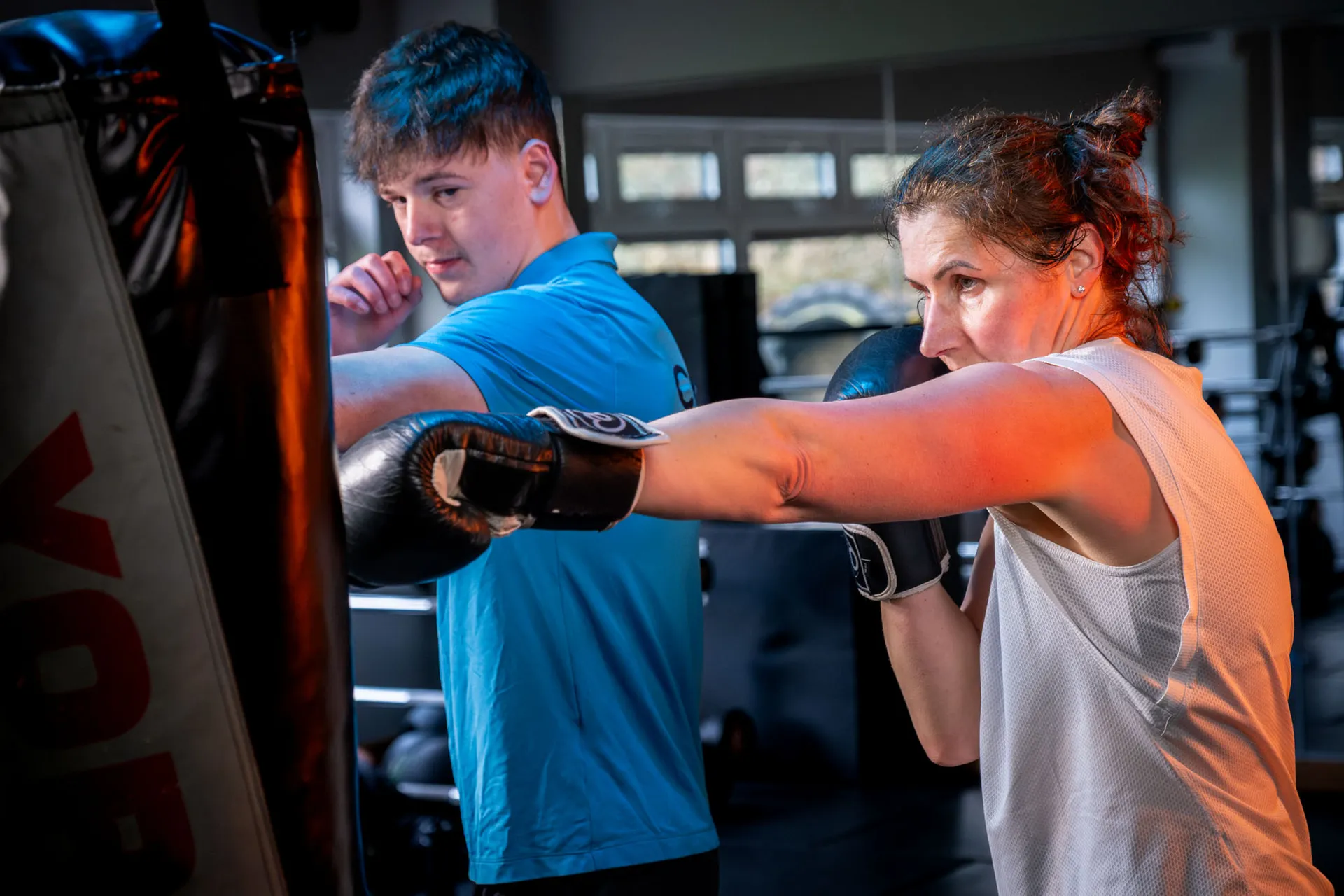 A West Coast Fitness trainer supervising a boxing bag session at the Peel gym on the Isle of Man, photographed for DotPerformance