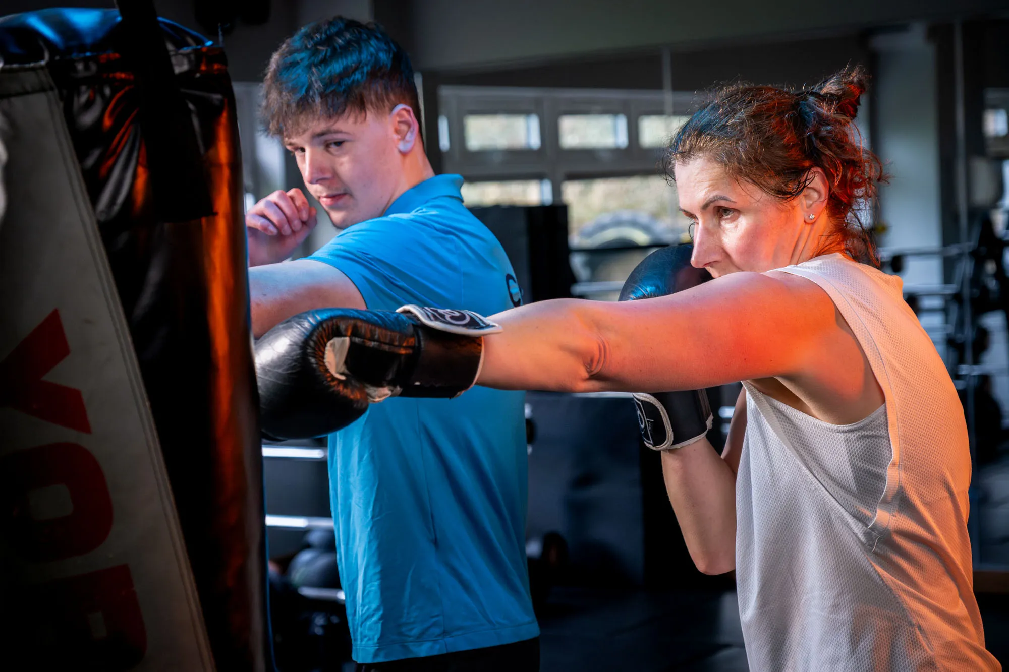 A West Coast Fitness trainer supervising a boxing bag session at the Peel gym on the Isle of Man, photographed for DotPerformance