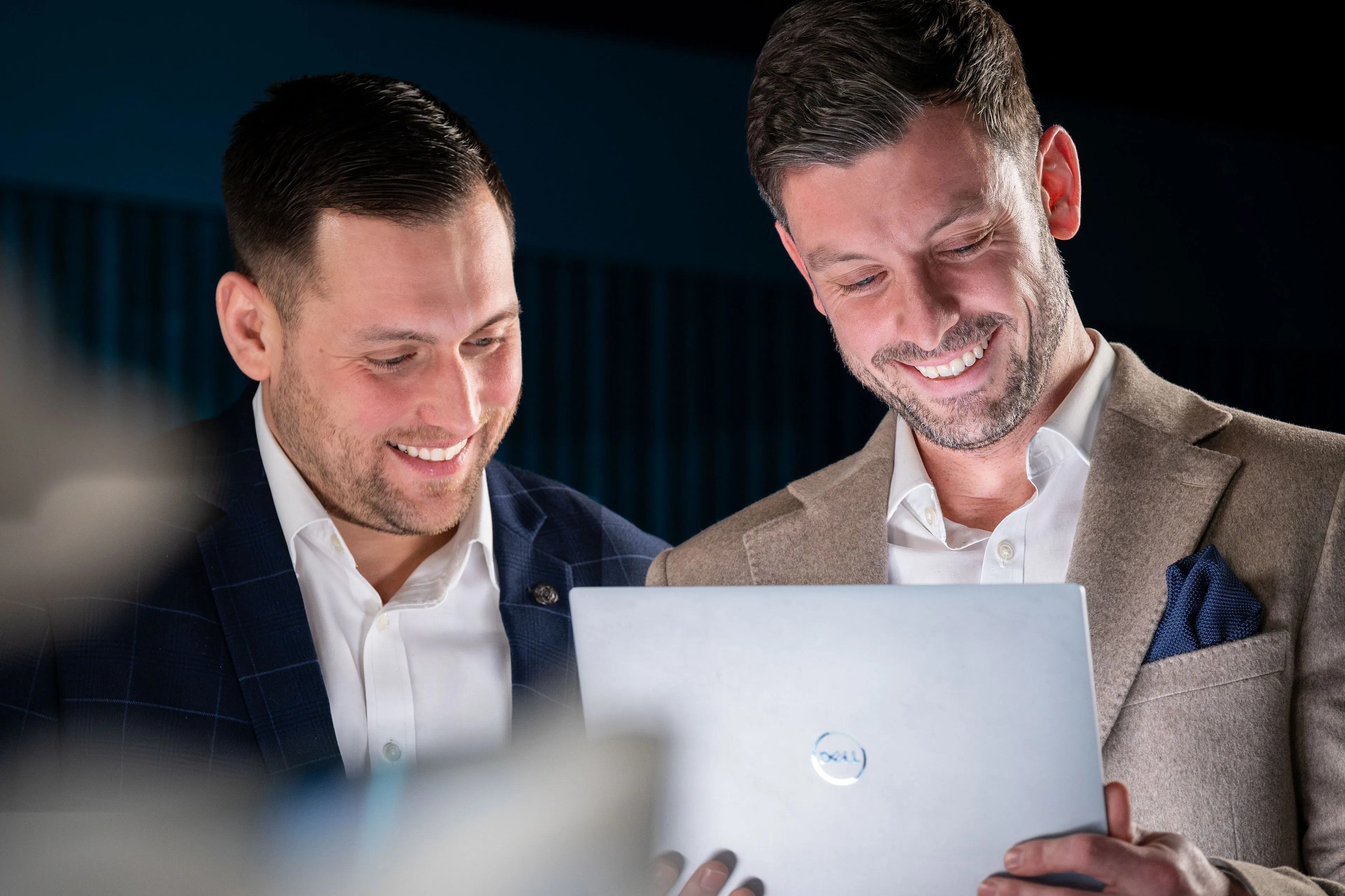 Dan Collier and Brook Longhurst smiling as they look down together at a laptop screen