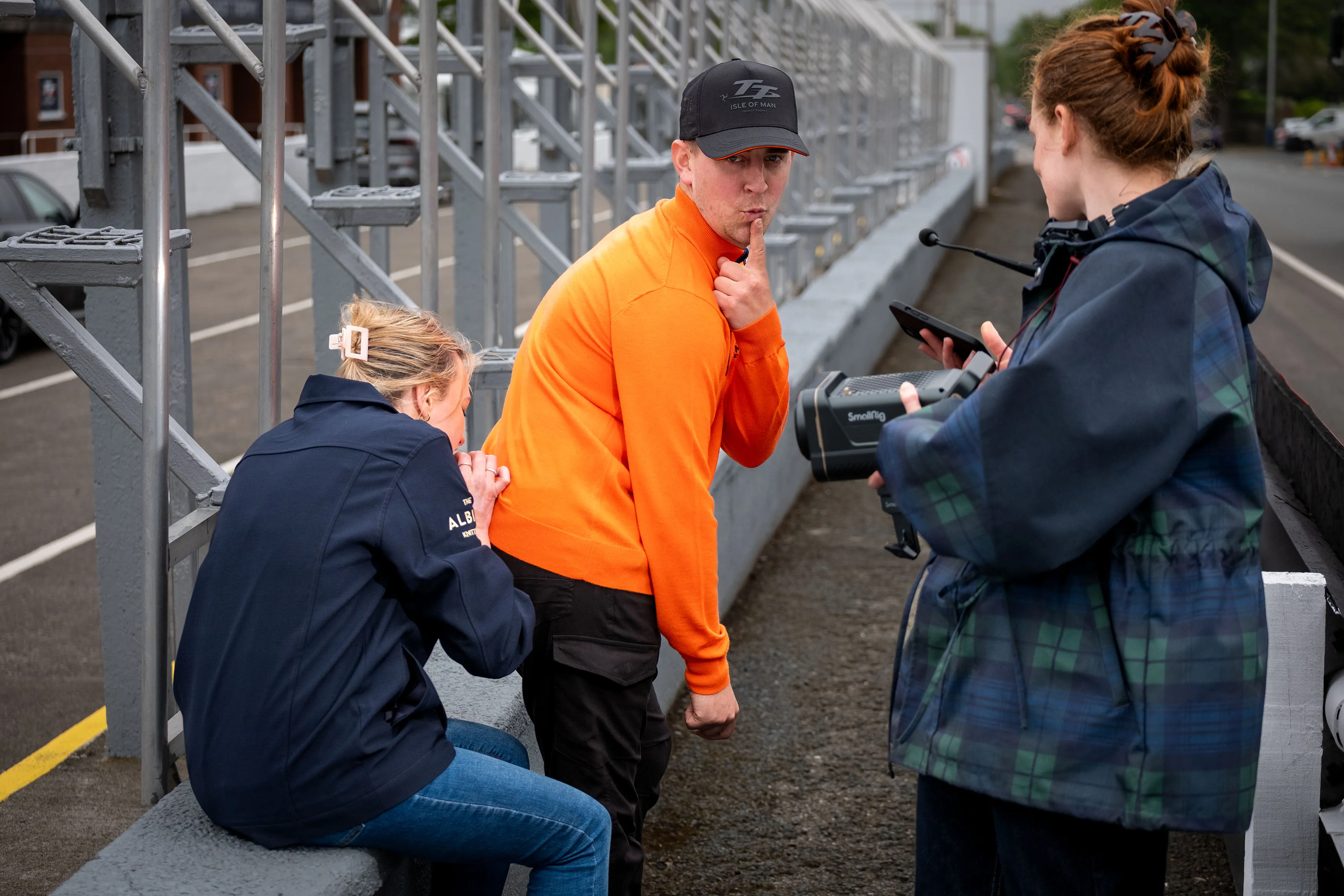 Behind the scenes as Maddi Scordia removes a tag from the jumper while professional TT rider Dom Herbertson jokes around at the TT Grandstand pitlane.