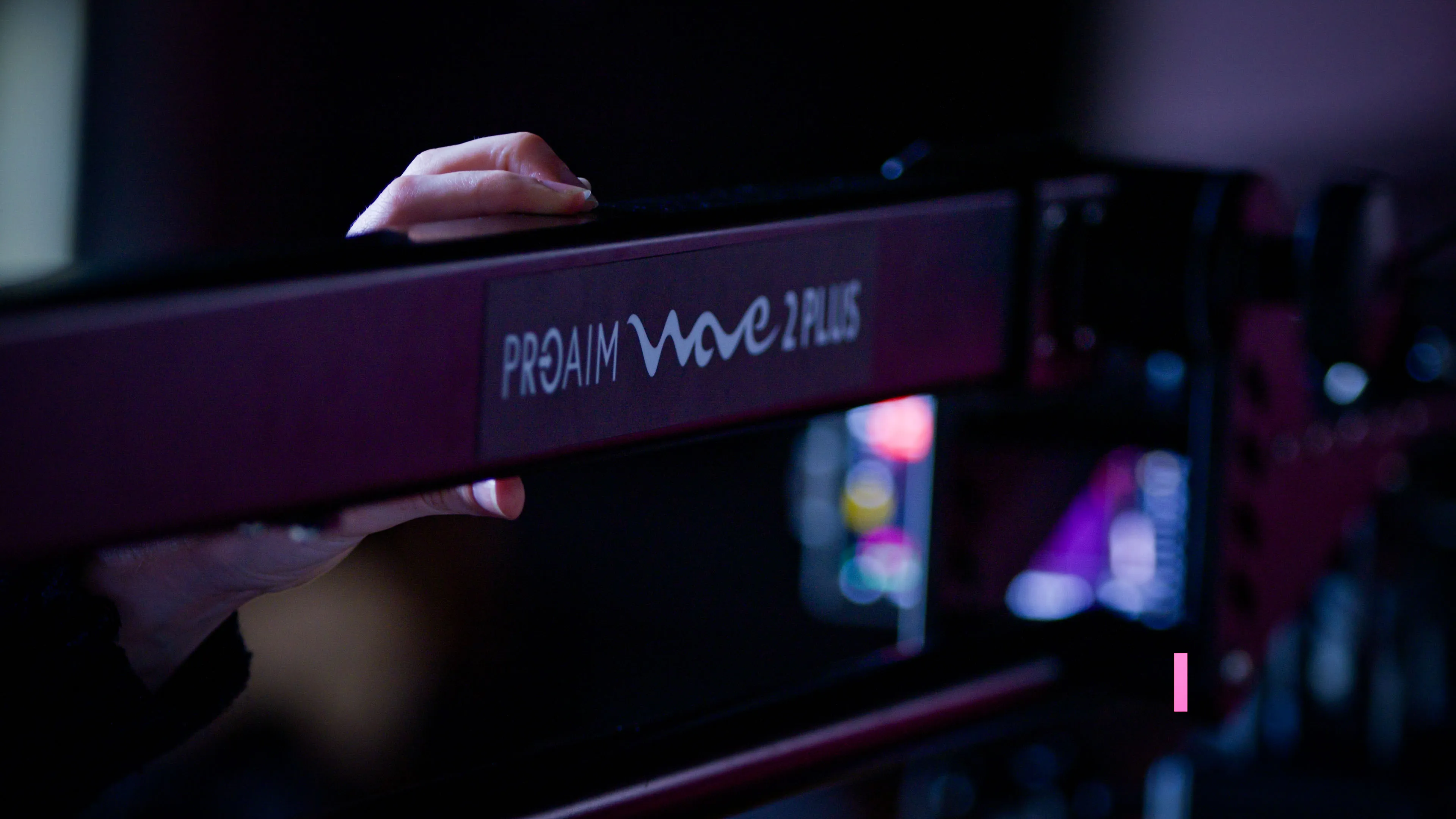 A person's hand adjusts a ProAim Wave 2 Plus camera jib in a dimly lit setting, suggesting careful and precise filmmaking or photography work.