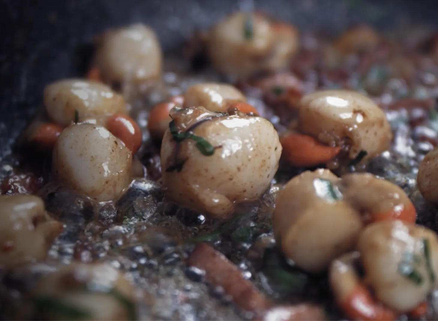 Close-up of queen scallops being cooked in a pan with herbs and sauce, shellfish product photography for Island Seafare