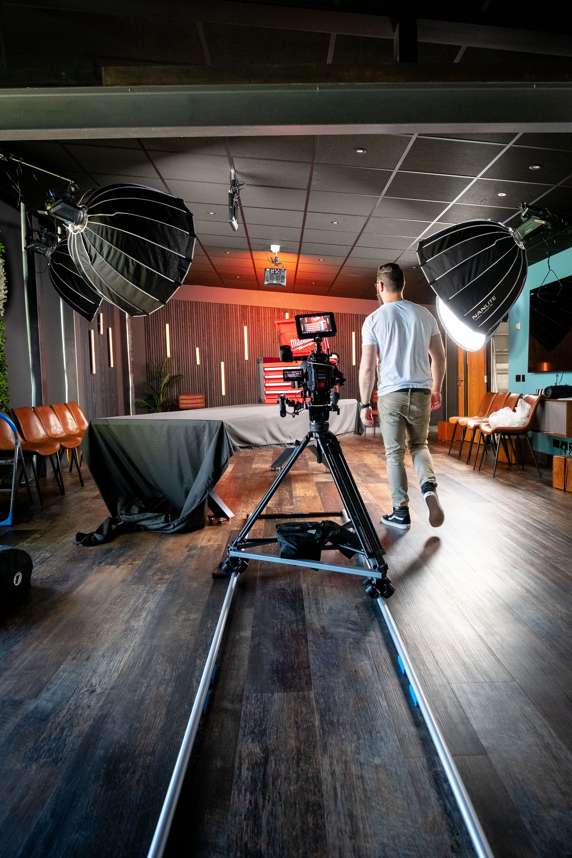 Wide shot of the PROAIM Swift Dolly System straight track set up in the DotPerformance Media Studio, with Nico van Loggerenberg walking towards the Milwaukee STC30-1 Toolbox prize set under studio lighting