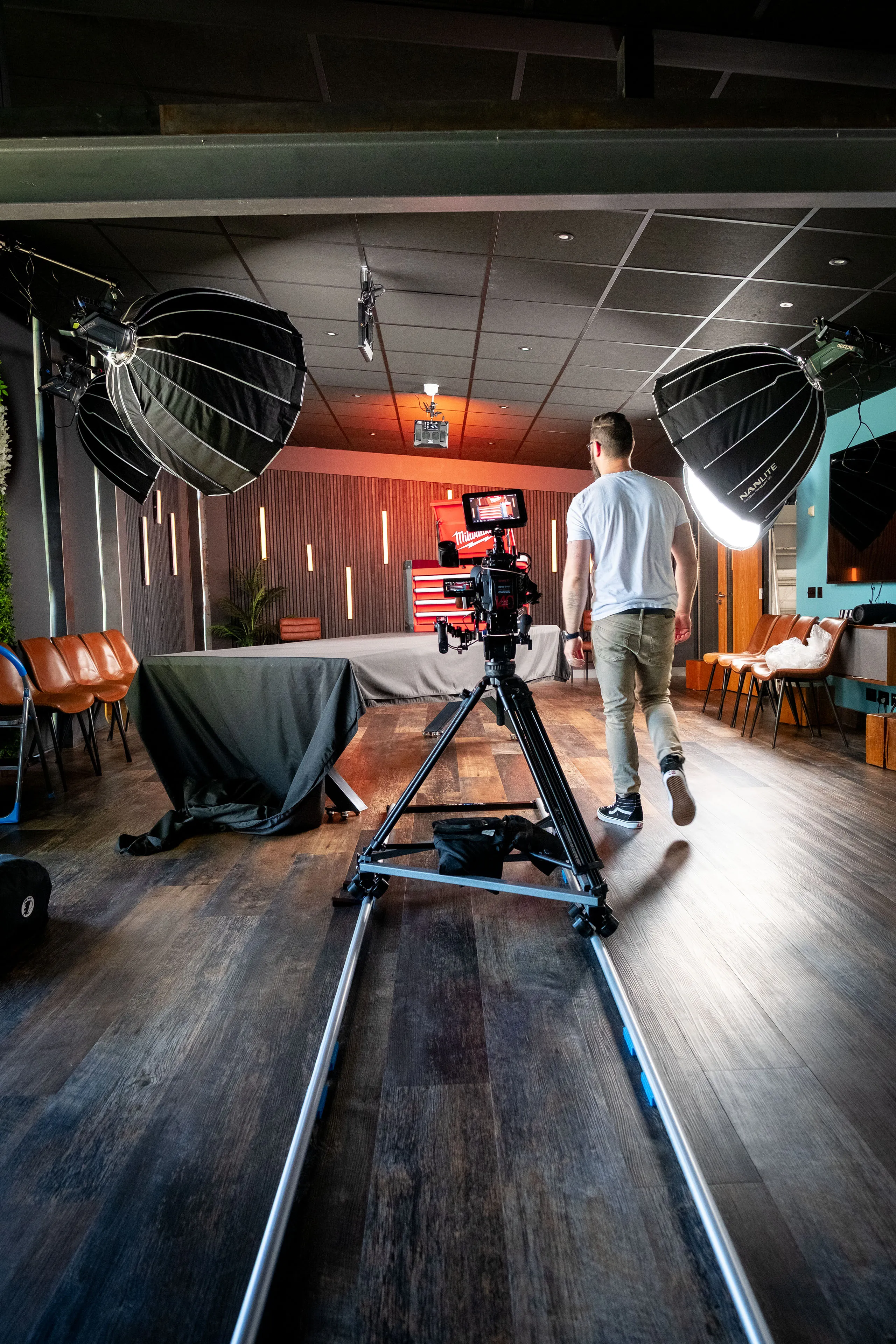 Wide shot of the PROAIM Swift Dolly System straight track set up in the DotPerformance Media Studio, with Nico van Loggerenberg walking towards the Milwaukee STC30-1 Toolbox prize set under studio lighting