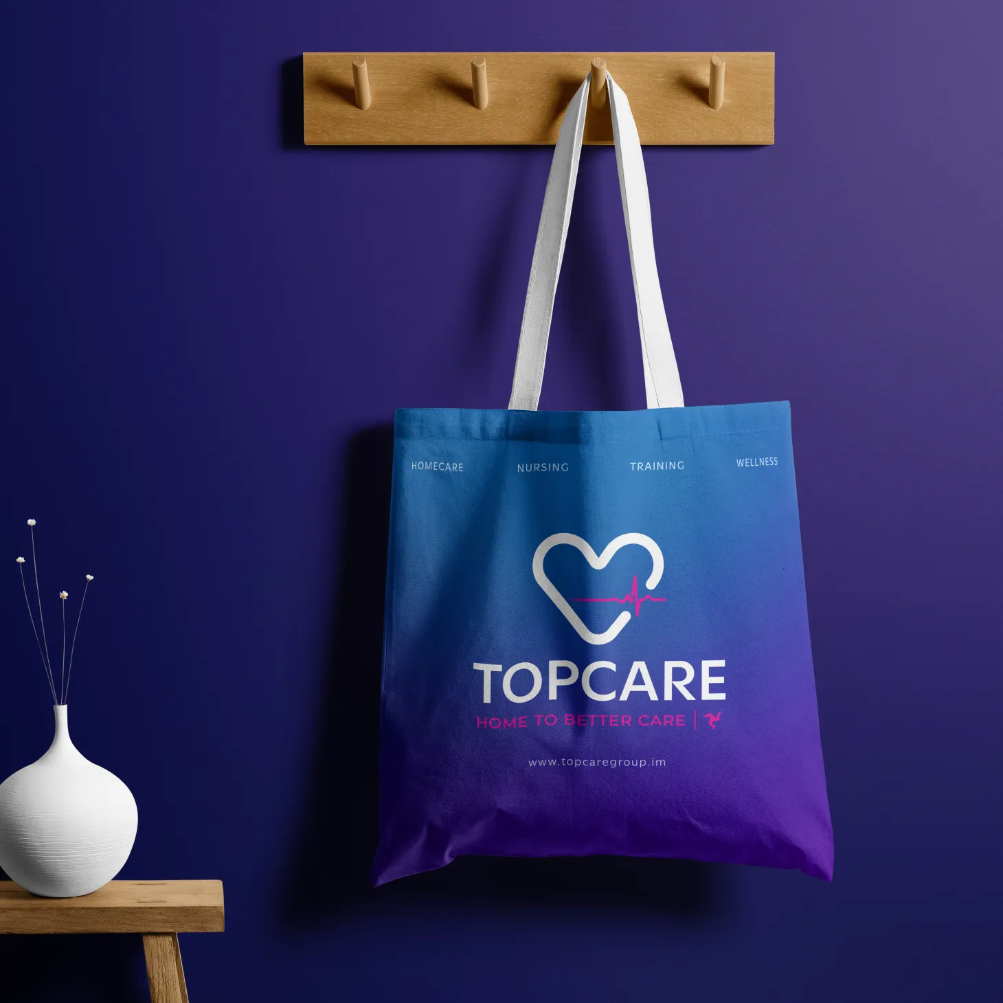 Blue tote bag with Topcare logo and tagline hanging on a wooden hook against a purple wall, healthcare promotional merchandise mockup